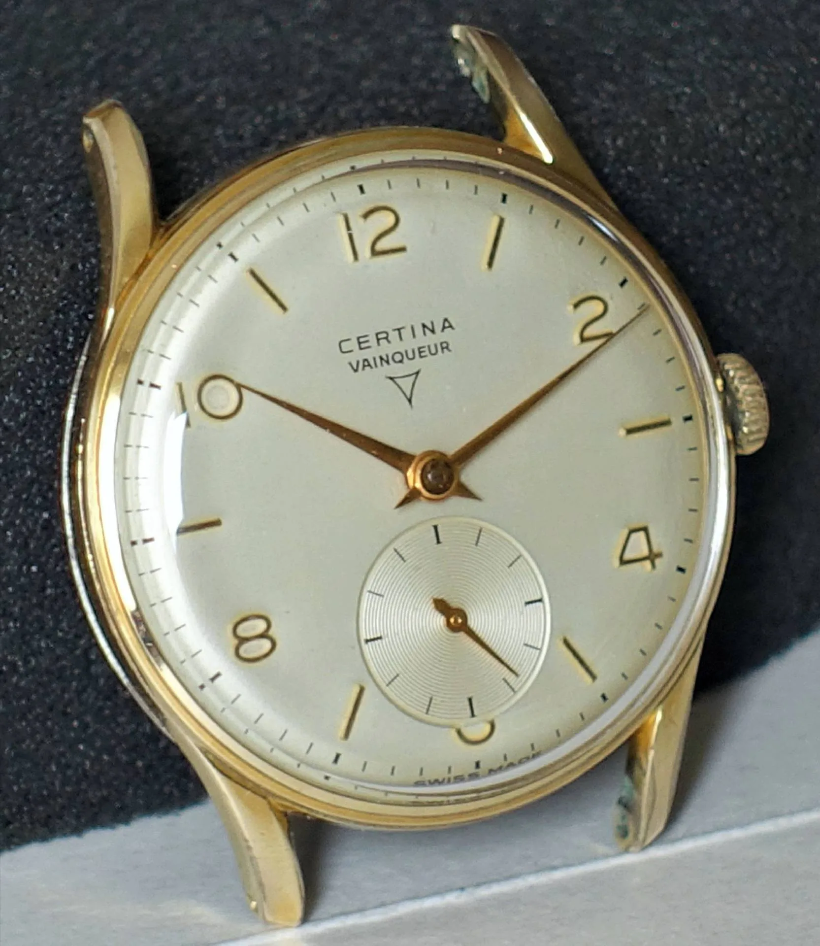 Runde Armbanduhr mit hellem Zifferblatt und goldfarbenem Gehäuse, Zeigern und Indizes.