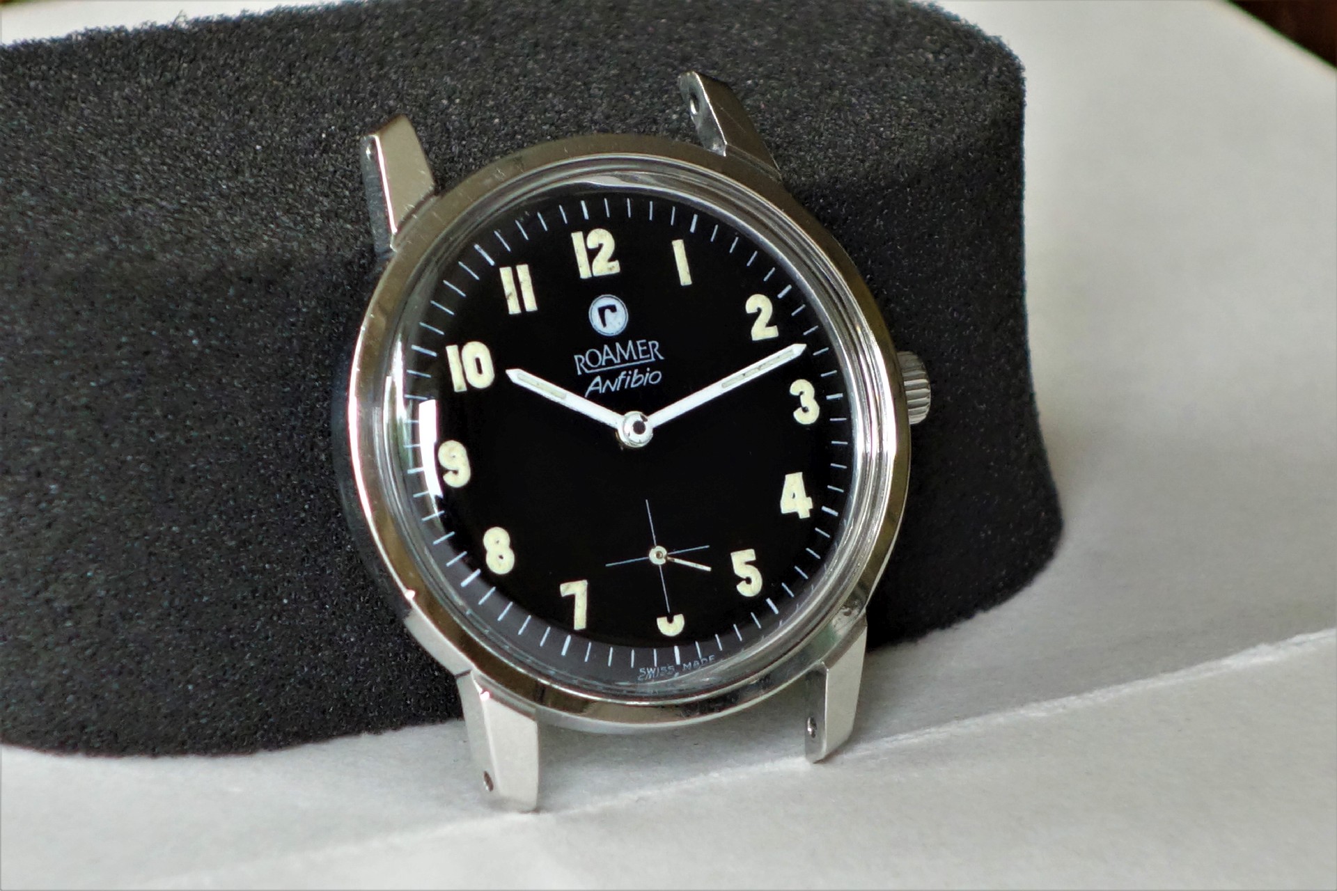 Schwarze Armbanduhr mit silberfarbenem Gehäuse und Leuchtziffern.