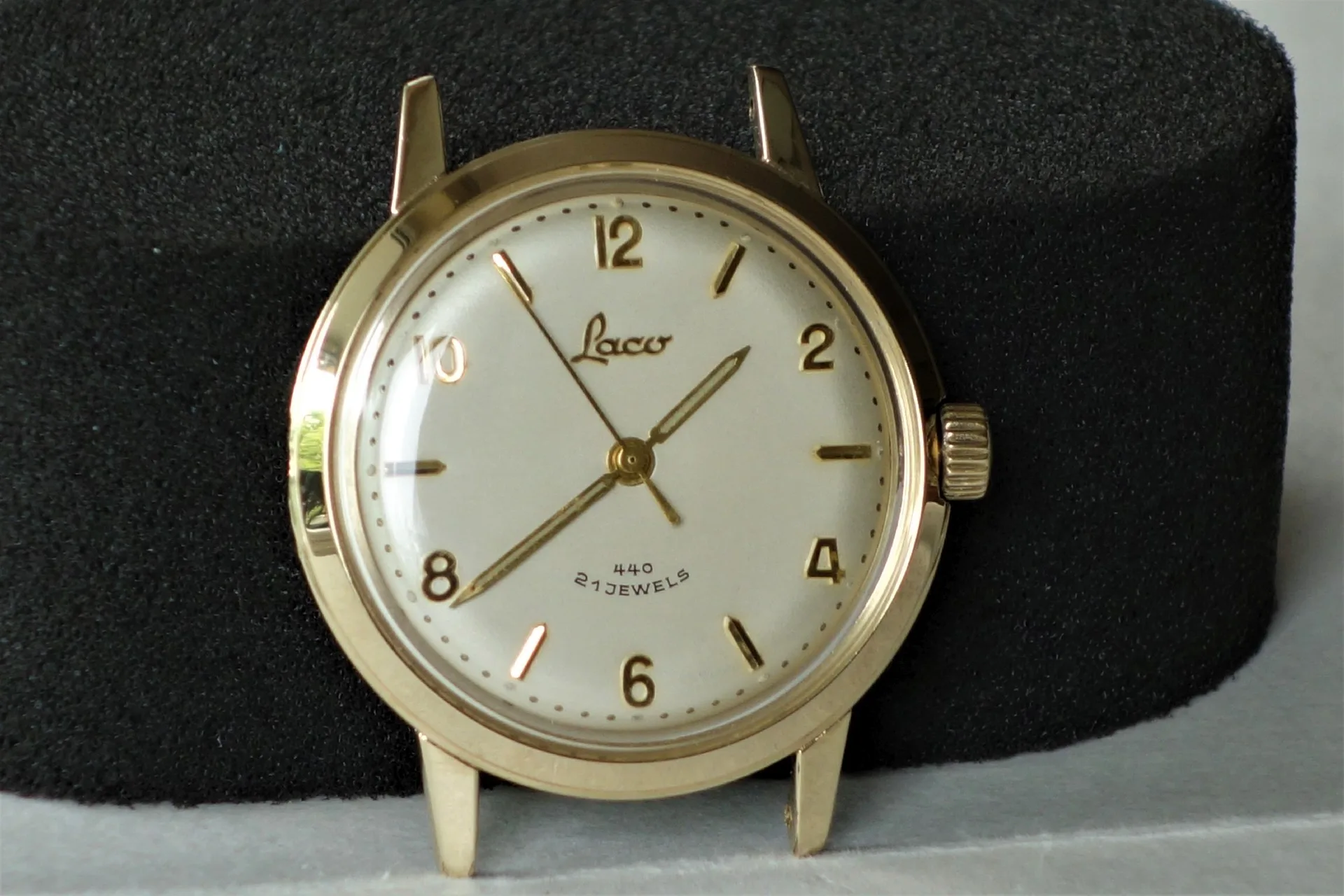 Runde Armbanduhr mit goldfarbenem Gehäuse und weißen Zifferblatt mit goldfarbenen Zahlen und Zeigern.