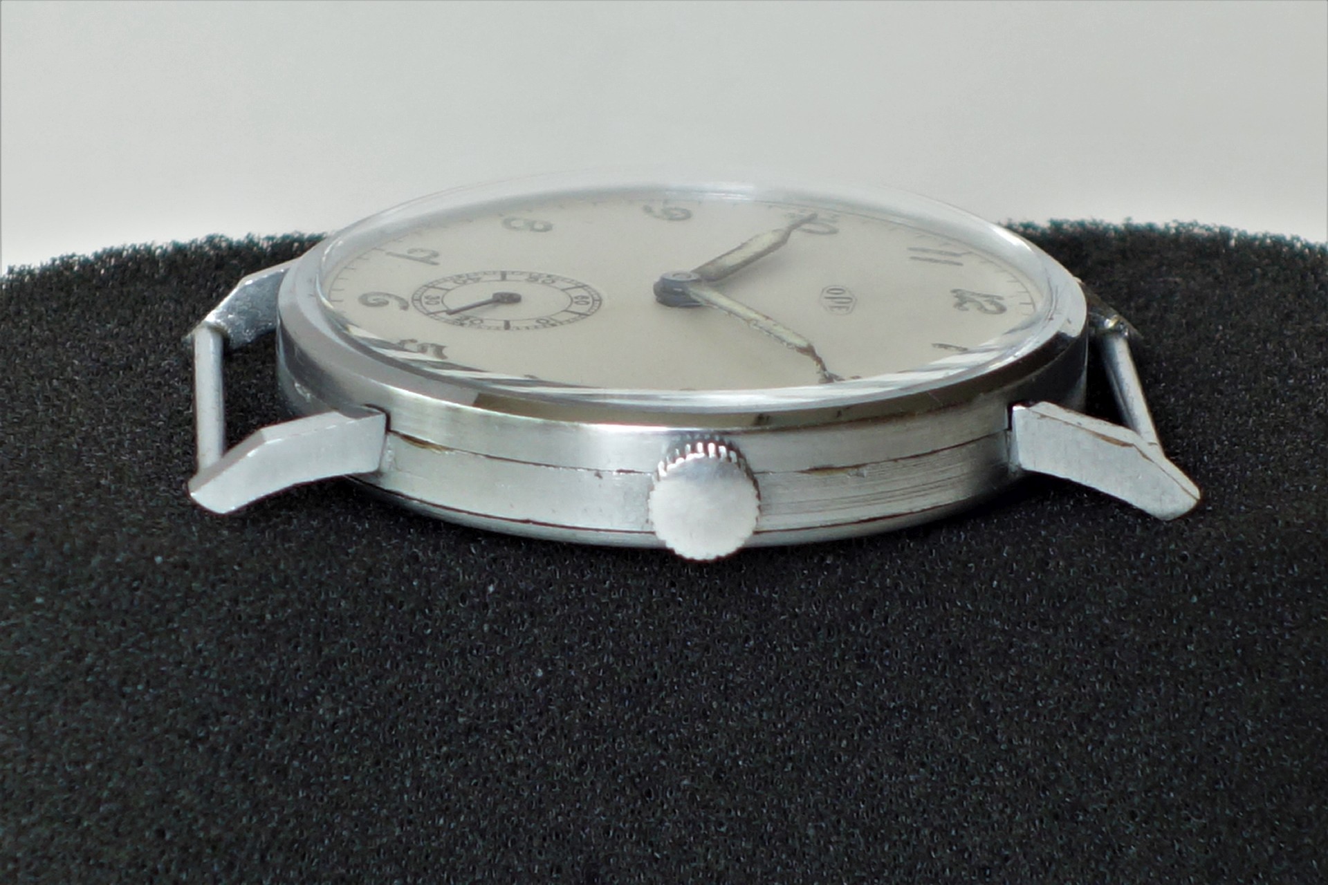 Flache Armbanduhr mit silberfarbenem Gehäuse und hellem Zifferblatt ohne Armband.