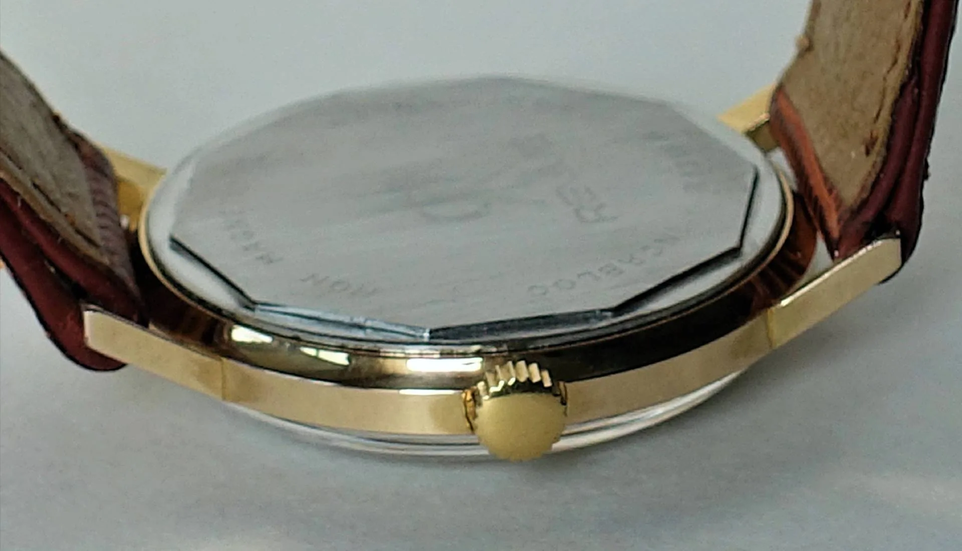 Armbanduhr goldfarben Flache Armbanduhr mit goldfarbenem Gehäuse, braunem Lederarmband und silberfarbener Rückseite.
