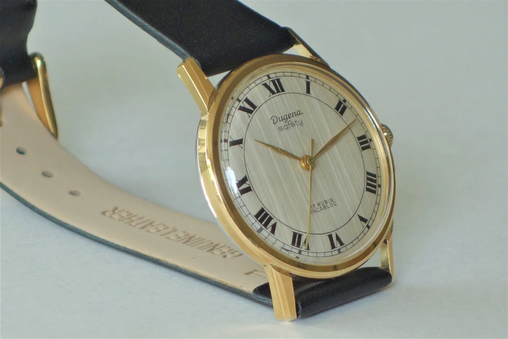 Klassische Armbanduhr goldfarben Runde Armbanduhr mit goldfarbenem Gehäuse, hellem Zifferblatt mit römischen Zahlen und schwarzem Armband.