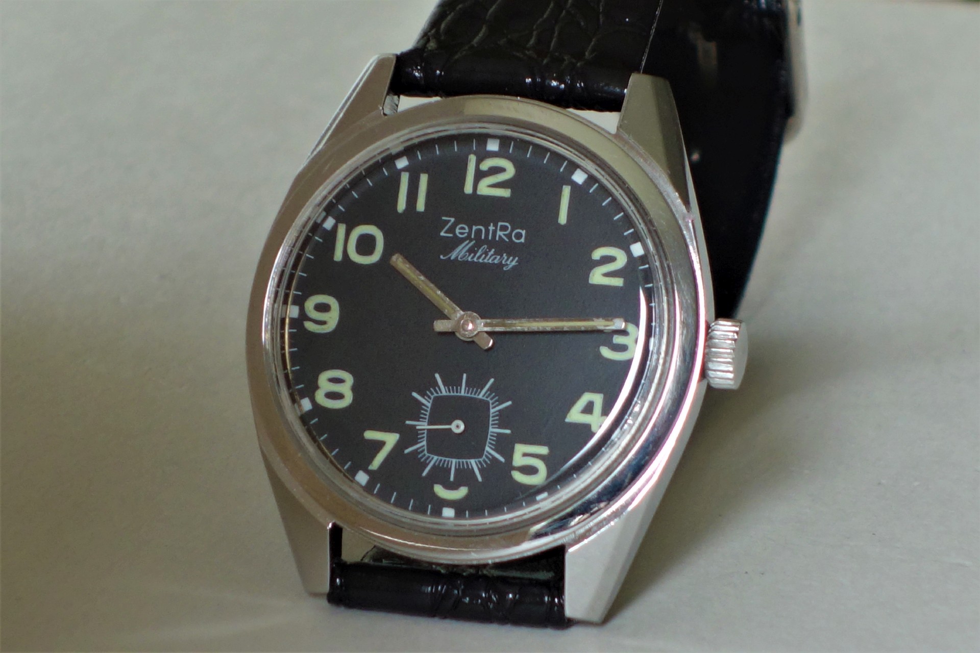 Schwarze Armbanduhr mit Leuchtziffern und schwarzem Armband.