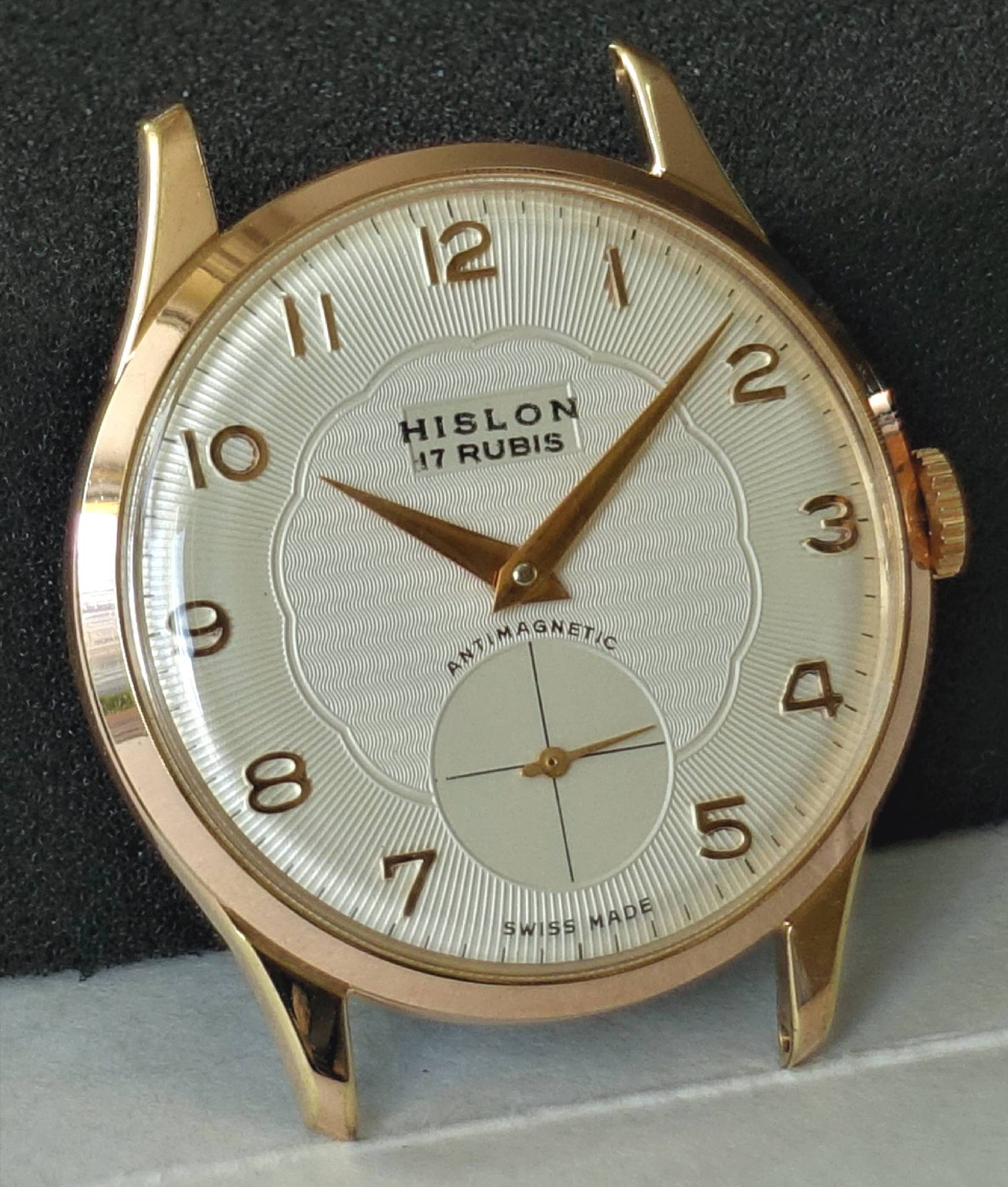 Eine Armbanduhr mit roségoldenem Gehäuse, weißem Zifferblatt, goldfarbenen Zahlen und Zeigern sowie kleiner Sekunde bei sechs Uhr.