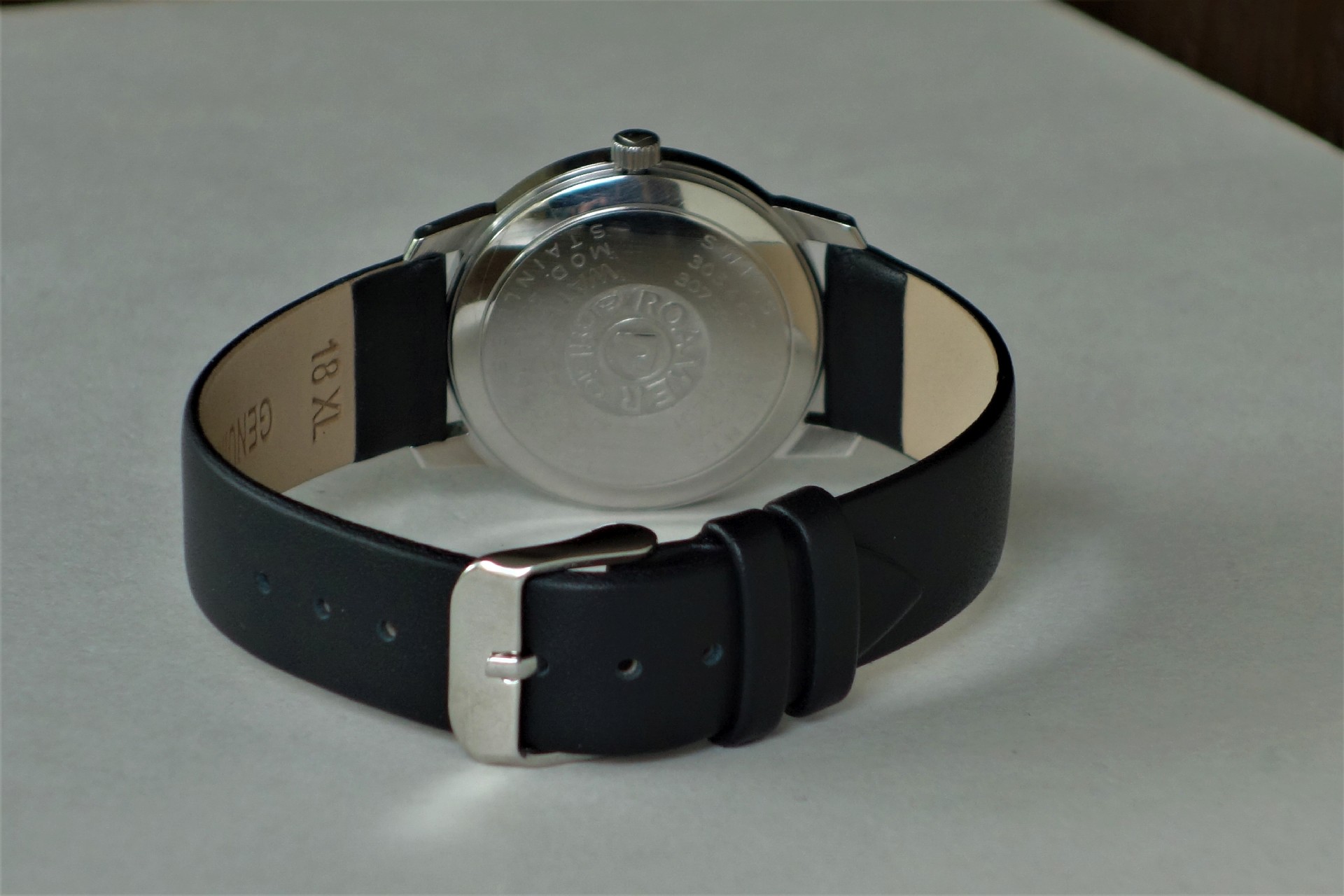 Armbanduhr mit schwarzem Armband und silberfarbener Rückseite.