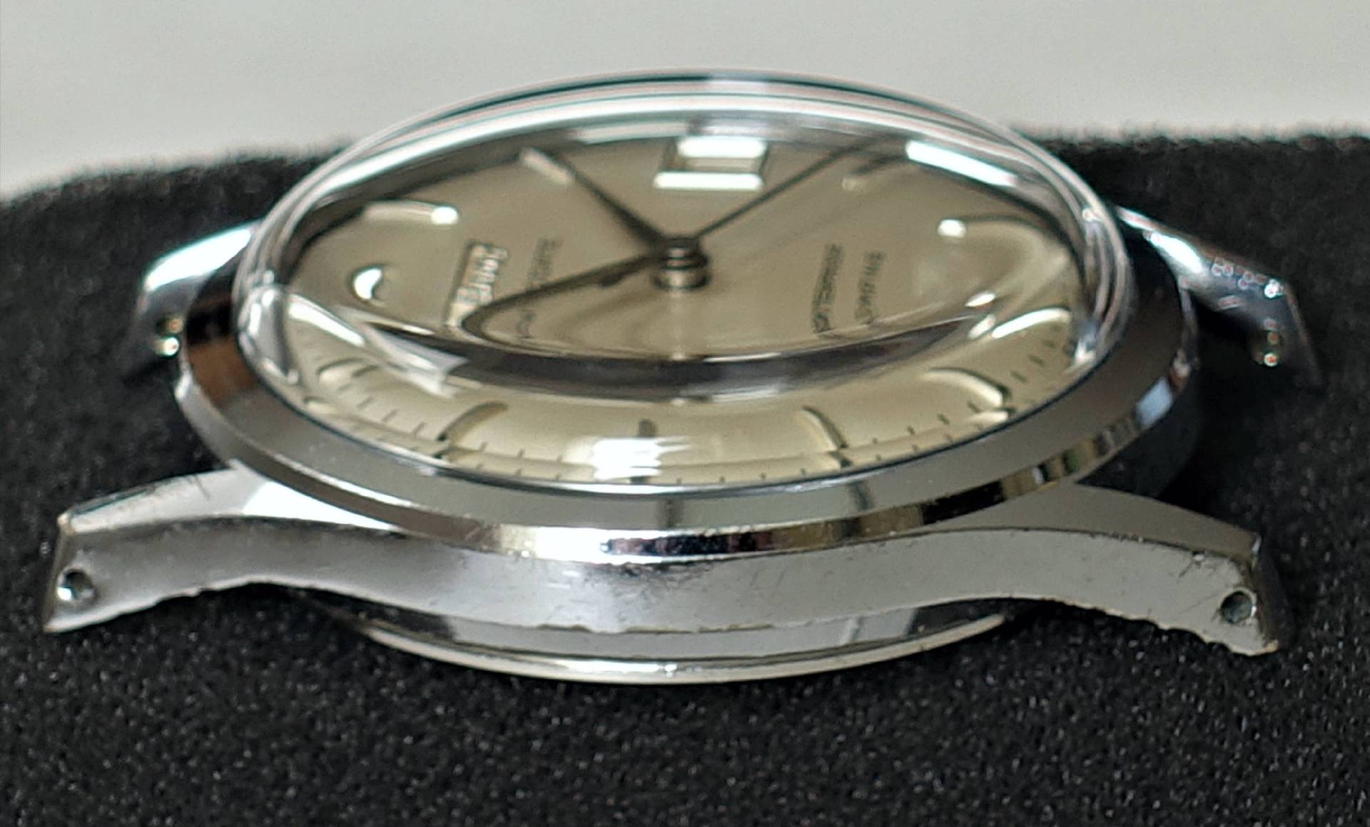 Silberfarbenes Uhrengehäuse mit montiertem Zifferblatt und Zeigern, aber ohne Armband.