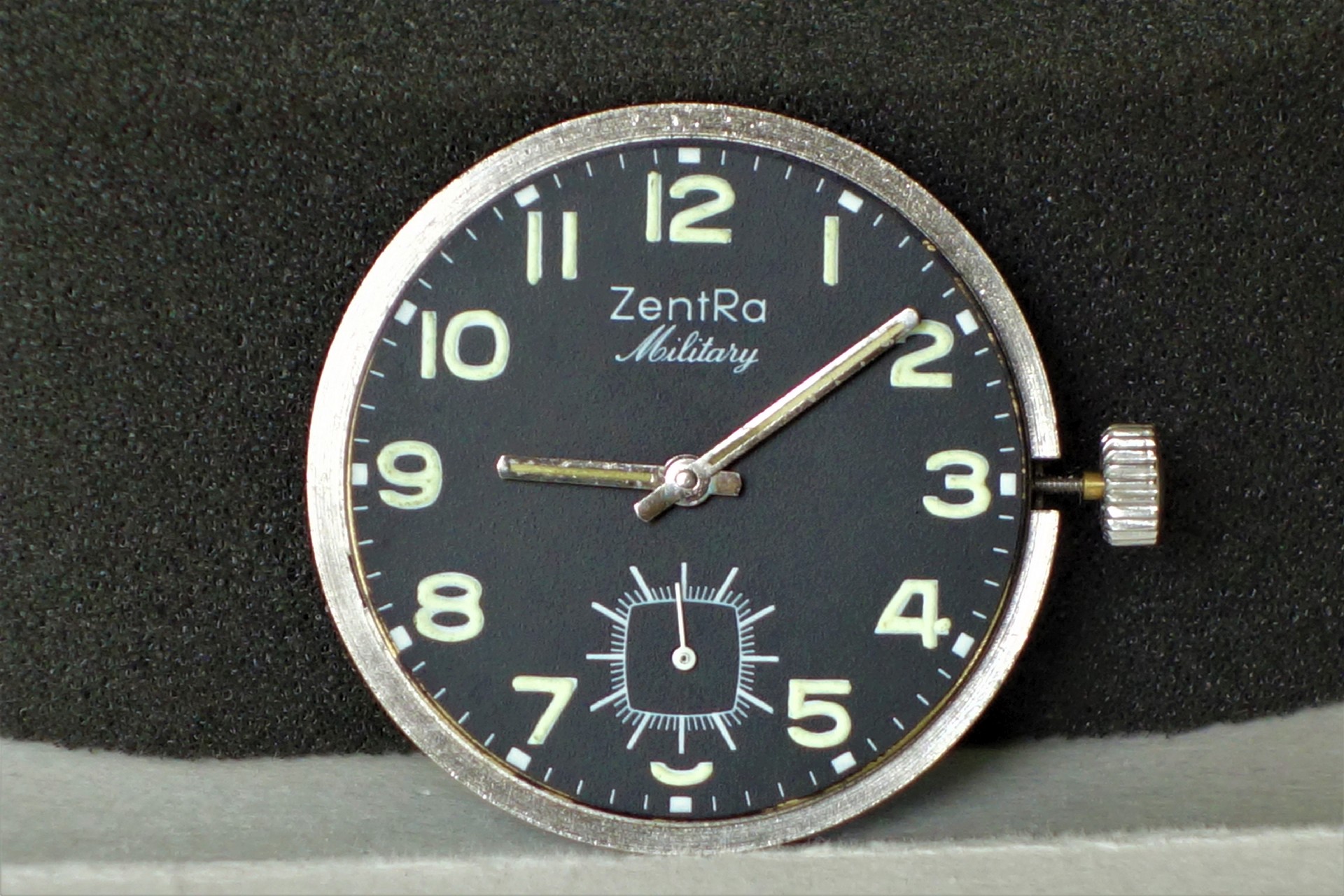 Schwarzes Uhrwerk mit silberner Krone und Leuchtzeigern, Zifferblatt mit Aufschrift "ZentRa Military".