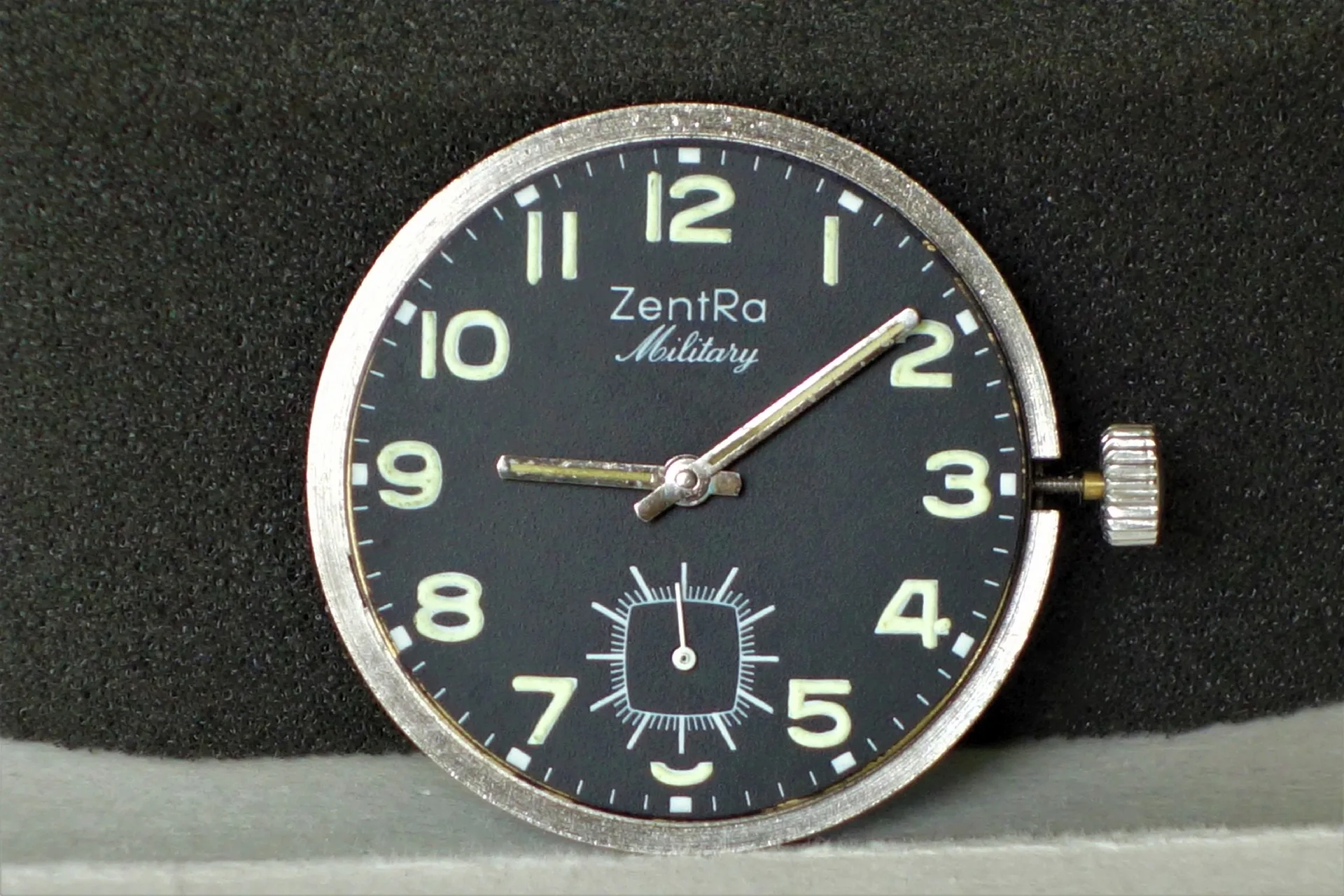 Schwarzes Uhrwerk mit silberner Krone und Leuchtzeigern, Zifferblatt mit Aufschrift "ZentRa Military".