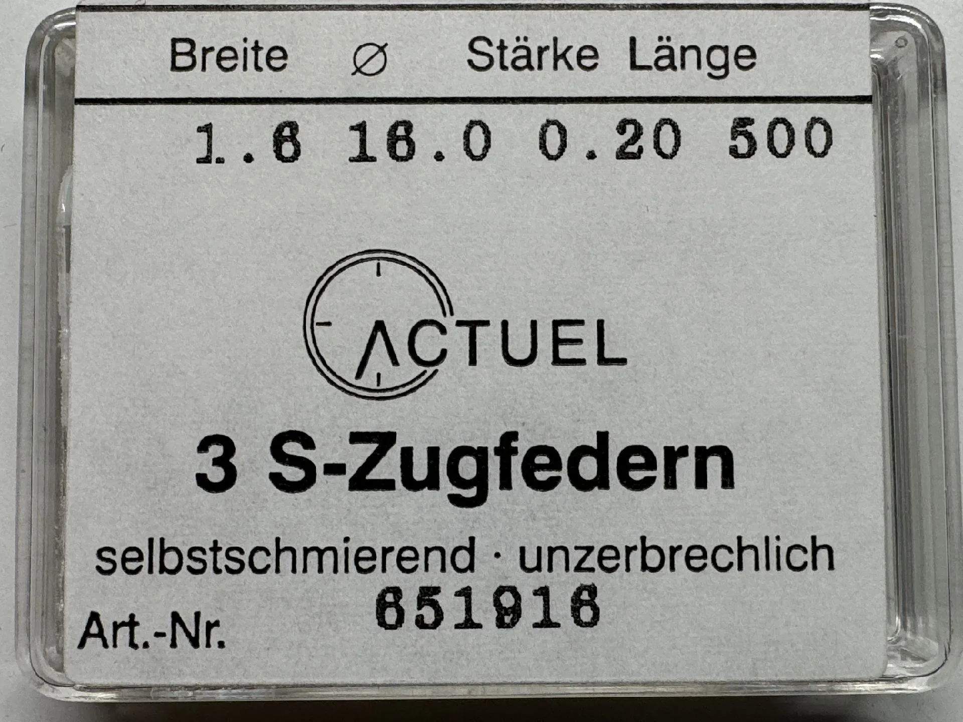 Zugfeder Set Drei silberfarbene Zugfedern für Uhren in transparenter Verpackung.