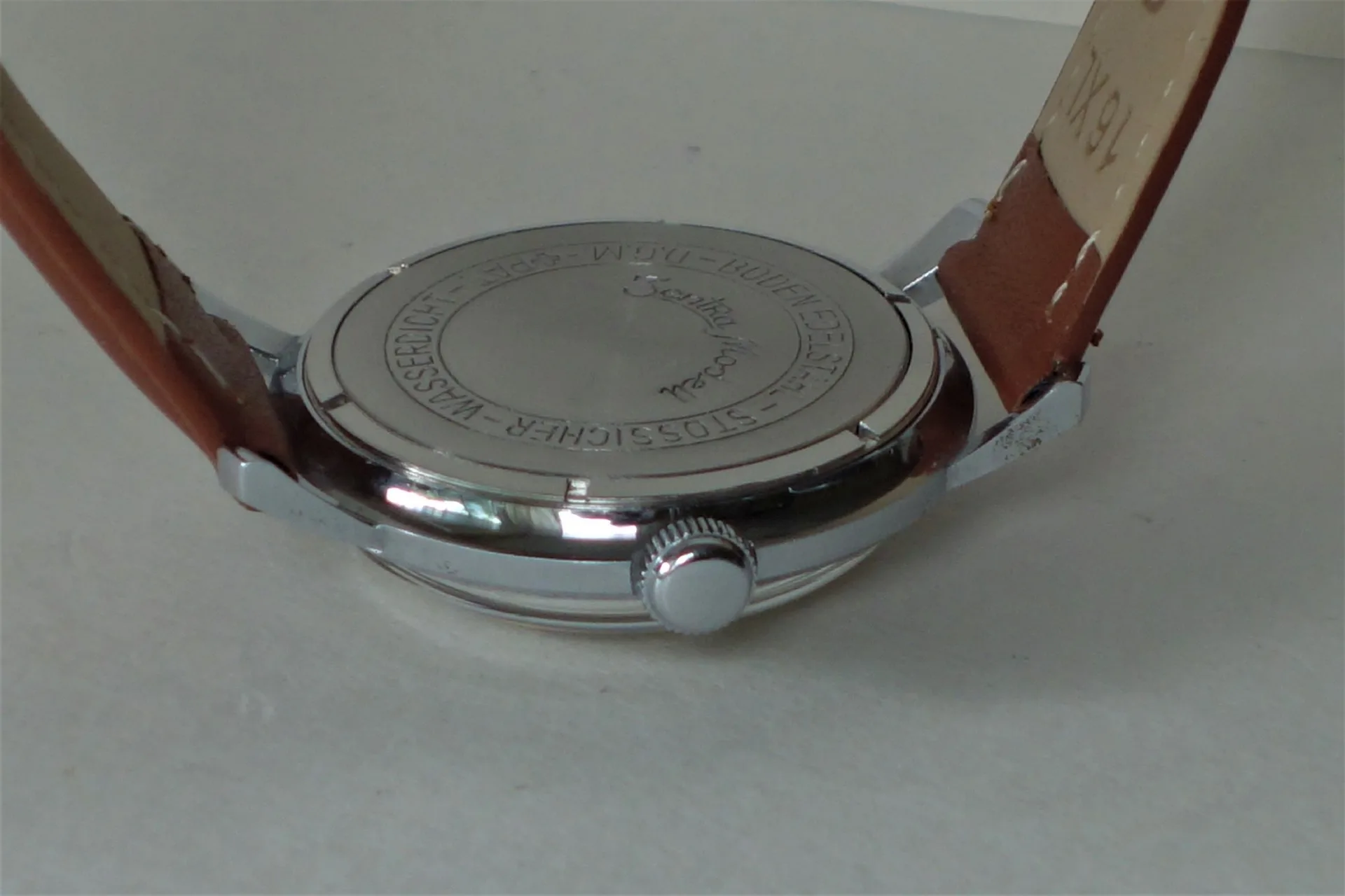 Uhrboden silberfarben Silberfarbener Uhrenboden mit Gravur und braunem Armband.