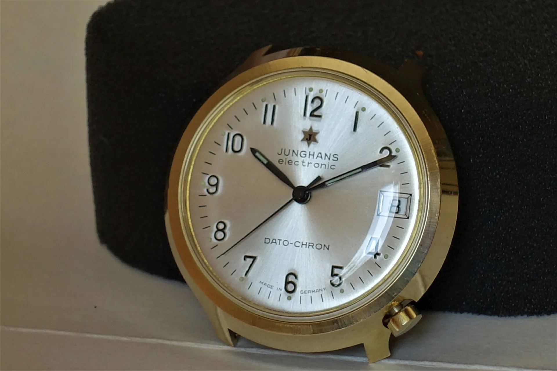 Junghans Dato-Chron Uhr Runde Uhr mit hellem Zifferblatt und goldfarbenem Gehäuse, Datumsanzeige bei drei Uhr.