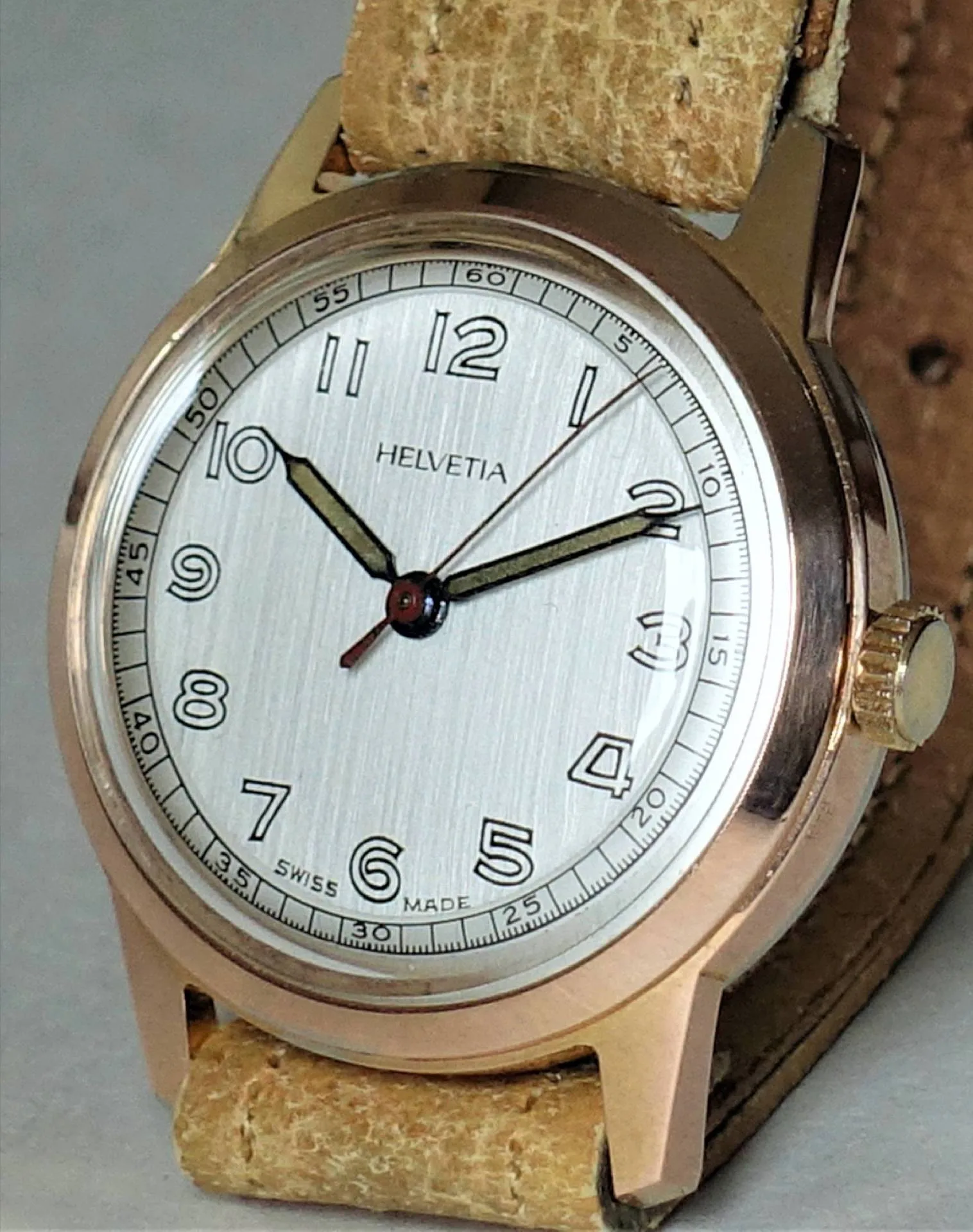 Helvetia Armbanduhr beige Beige Armbanduhr mit hellem Zifferblatt und schwarzen Zeigern, Gehäuse in goldfarbener Optik.