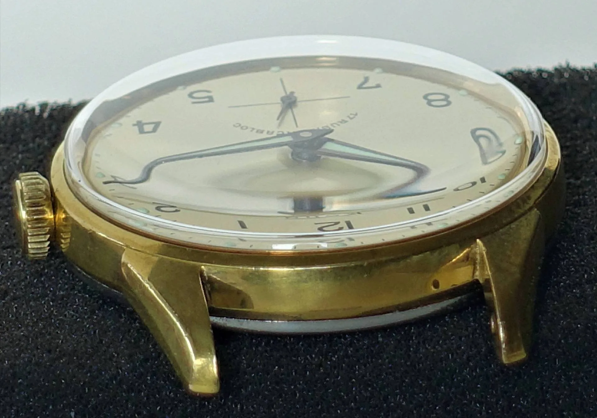 Goldfarbene Armbanduhr mit hellem Zifferblatt und schwarzen Zahlen.