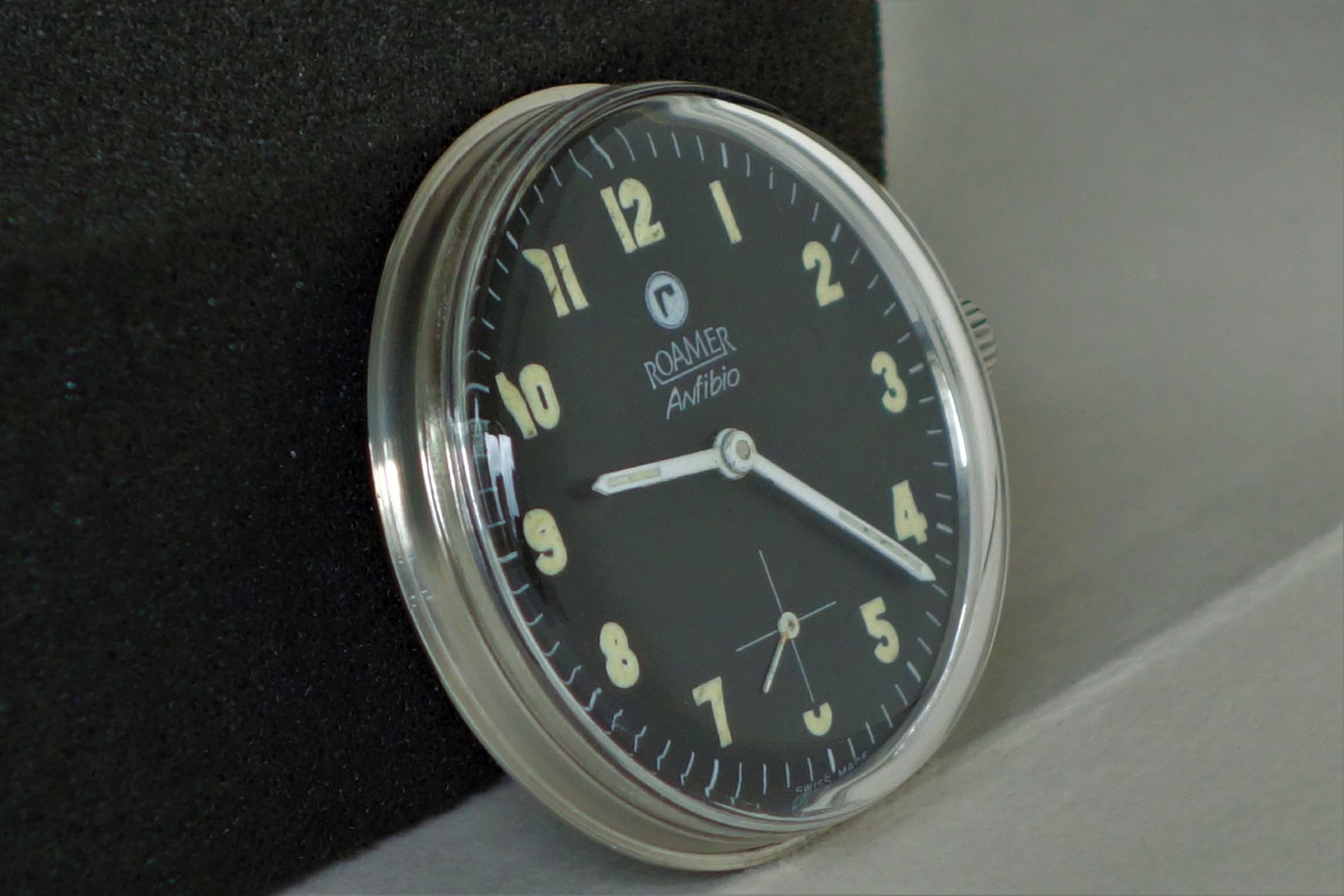 Schwarzes Uhrwerk mit Zifferblatt und Zeigern, Gehäuse silberfarben, Marke Roamer Anfibio.