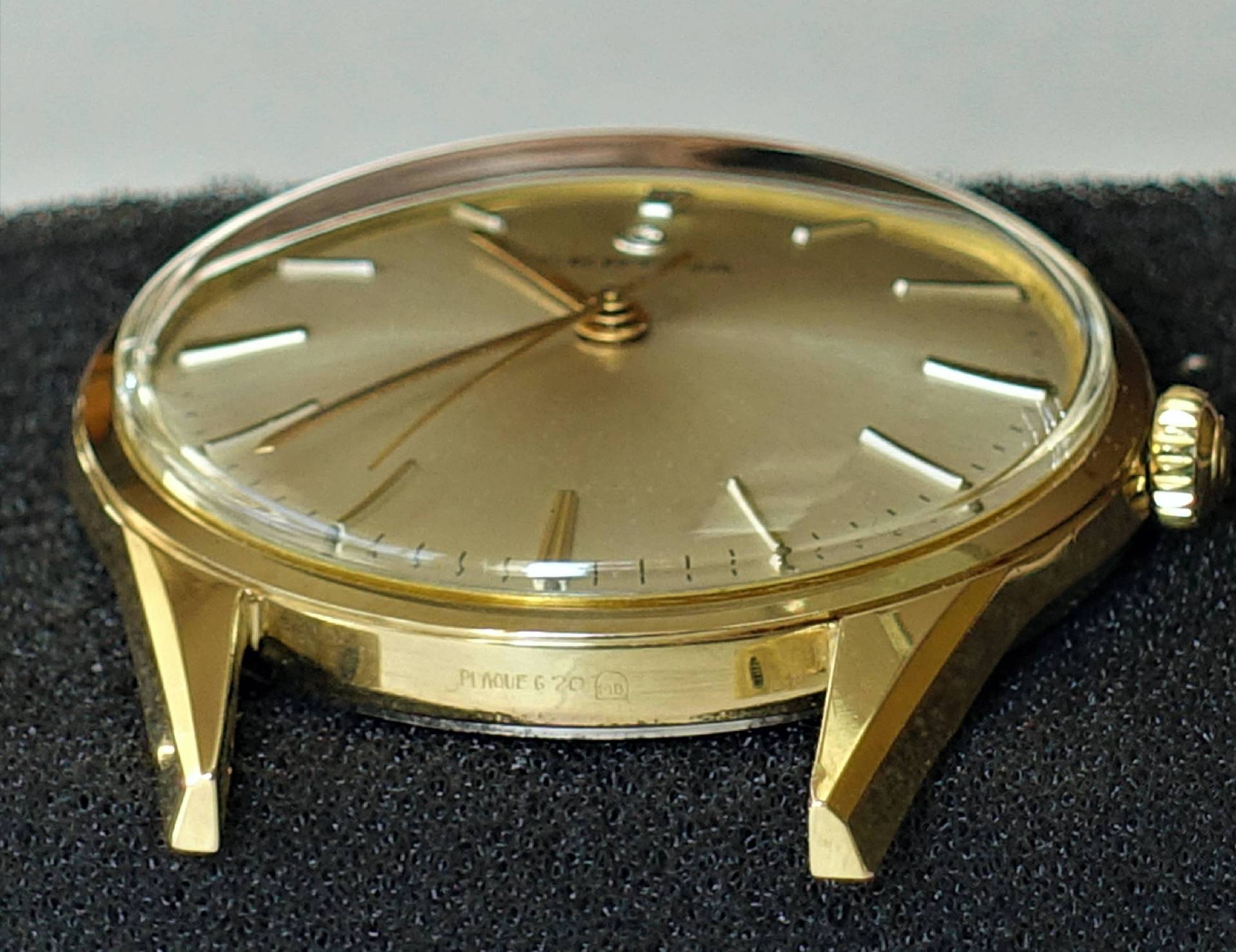 Flache Armbanduhr mit goldfarbenem Gehäuse und Zifferblatt sowie schlichten Indizes.