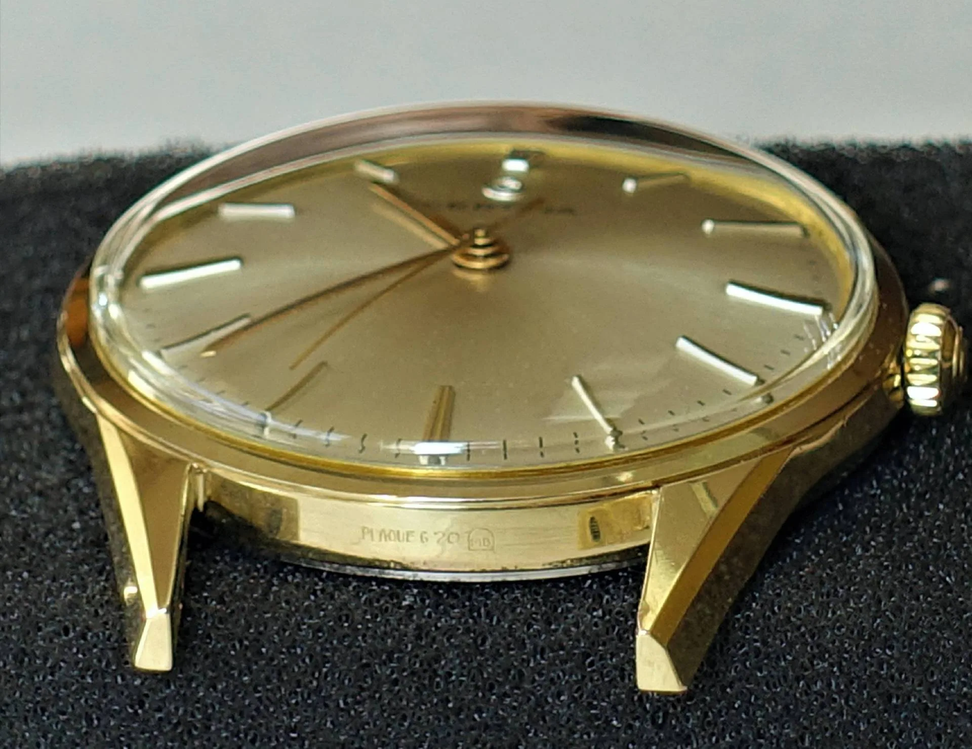 Flache Armbanduhr mit goldfarbenem Gehäuse und Zifferblatt sowie schlichten Indizes.