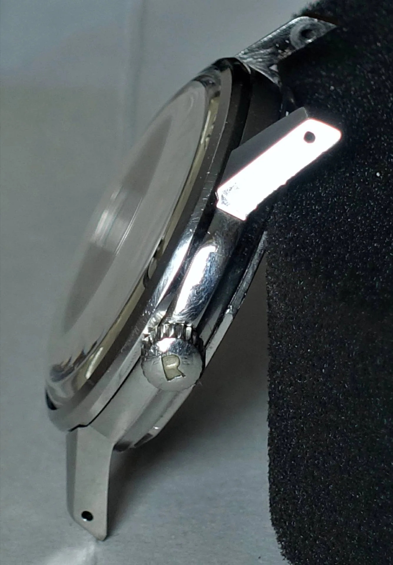 Elegante Uhr mit glänzendem Gehäuse und kratzfestem Glas Seitenansicht einer hochwertigen Uhr mit silbernem Gehäuse und präziser Uhrwerk-Funktionalität