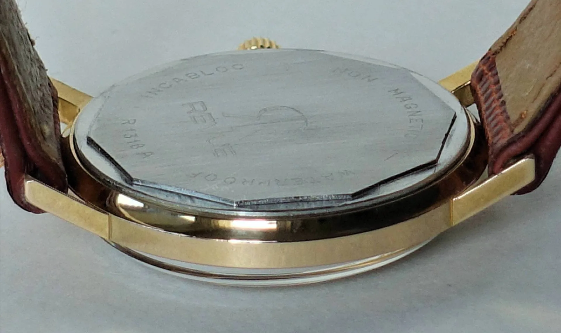 Uhrboden silberfarben Silberfarbener Uhrboden einer Armbanduhr mit goldfarbenem Gehäuse und braunem Lederarmband.