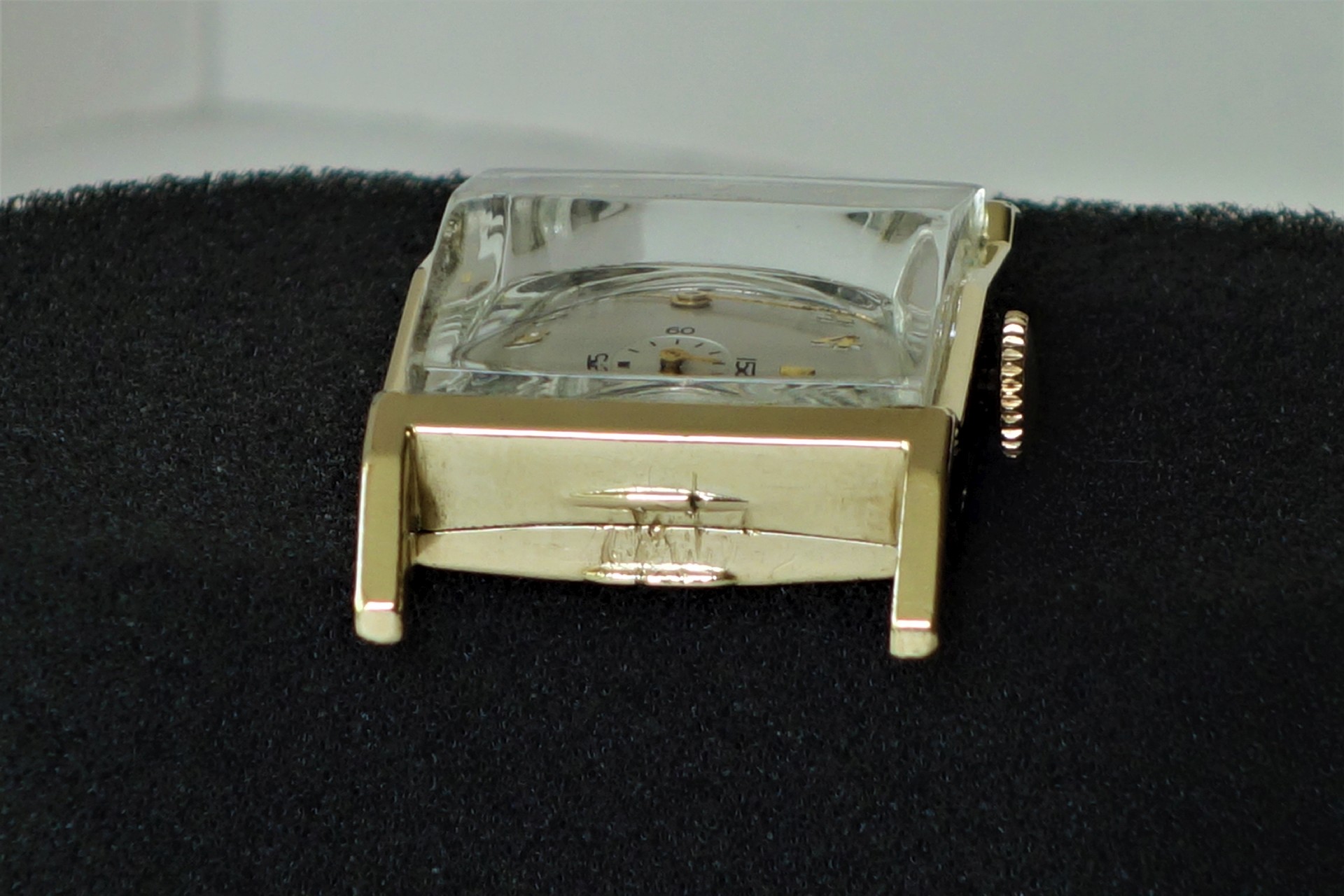 Rechteckiges Uhrengehäuse in goldfarbener Ausführung mit Glasabdeckung und sichtbarer Krone.