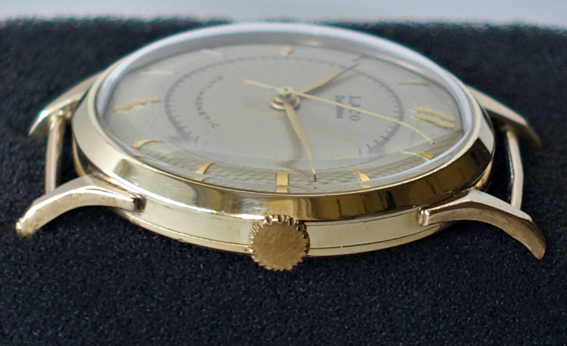 Analoge Armbanduhr mit goldfarbenem Gehäuse und Zeigern auf hellem Zifferblatt.