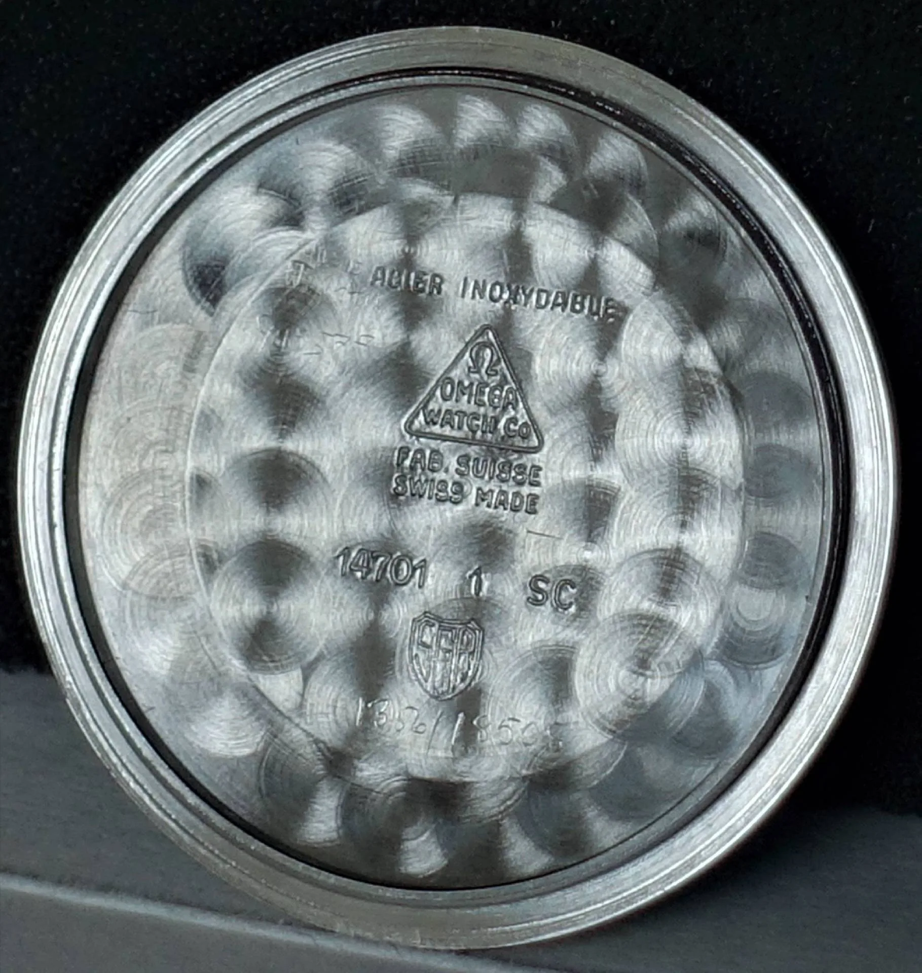 Silberfarbener Gehäuseboden einer Omega Uhr mit eingravierten Herstellerangaben und Referenznummern.