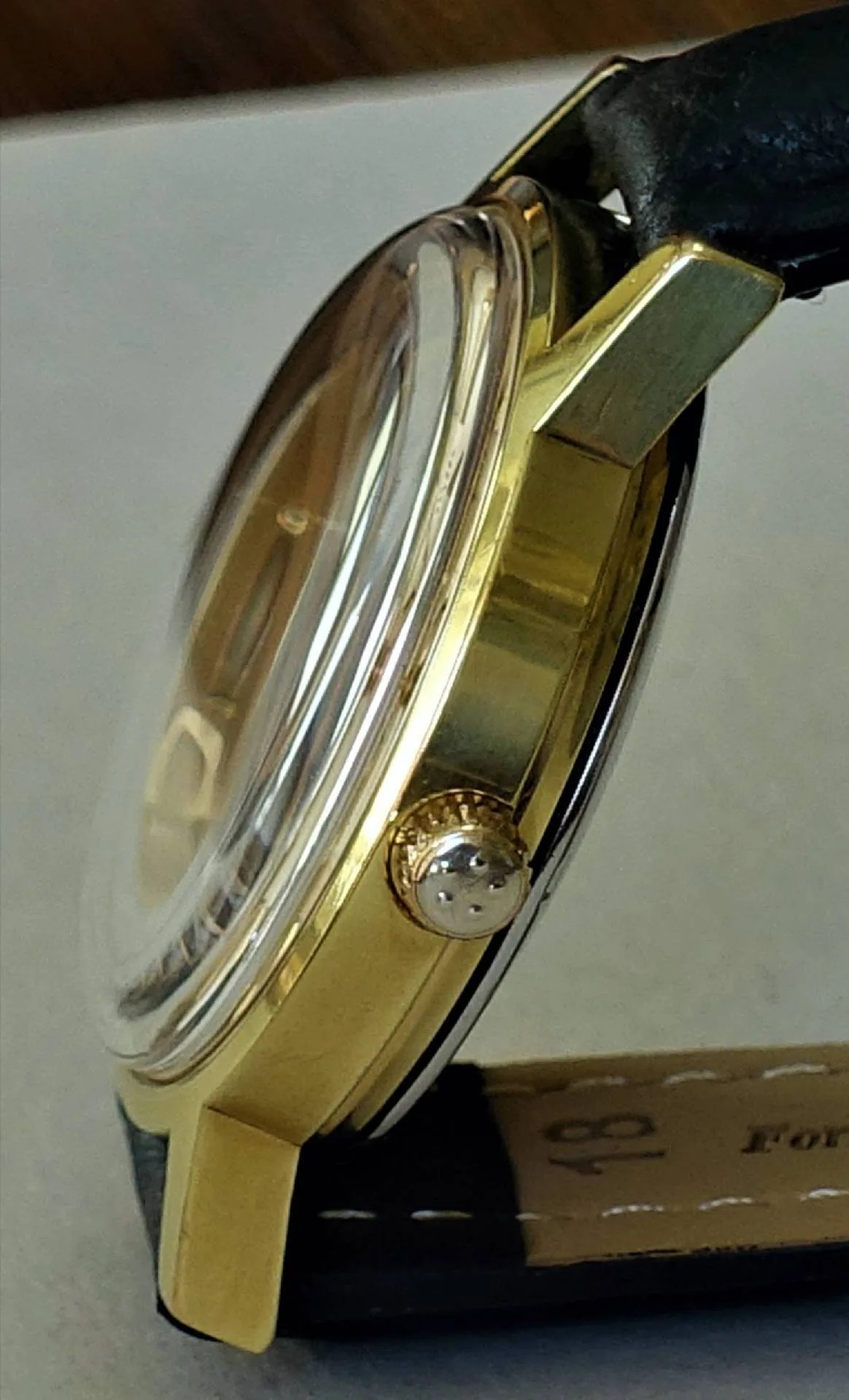 Armbanduhr goldfarben Goldfarbene Armbanduhr mit schwarzem Lederarmband und gewölbtem Uhrglas.