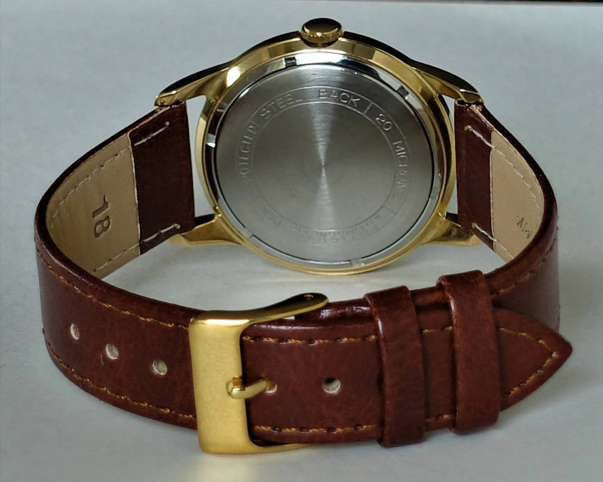 Armbanduhr mit braunem Armband und goldfarbenem Gehäuse, Rückseite sichtbar.