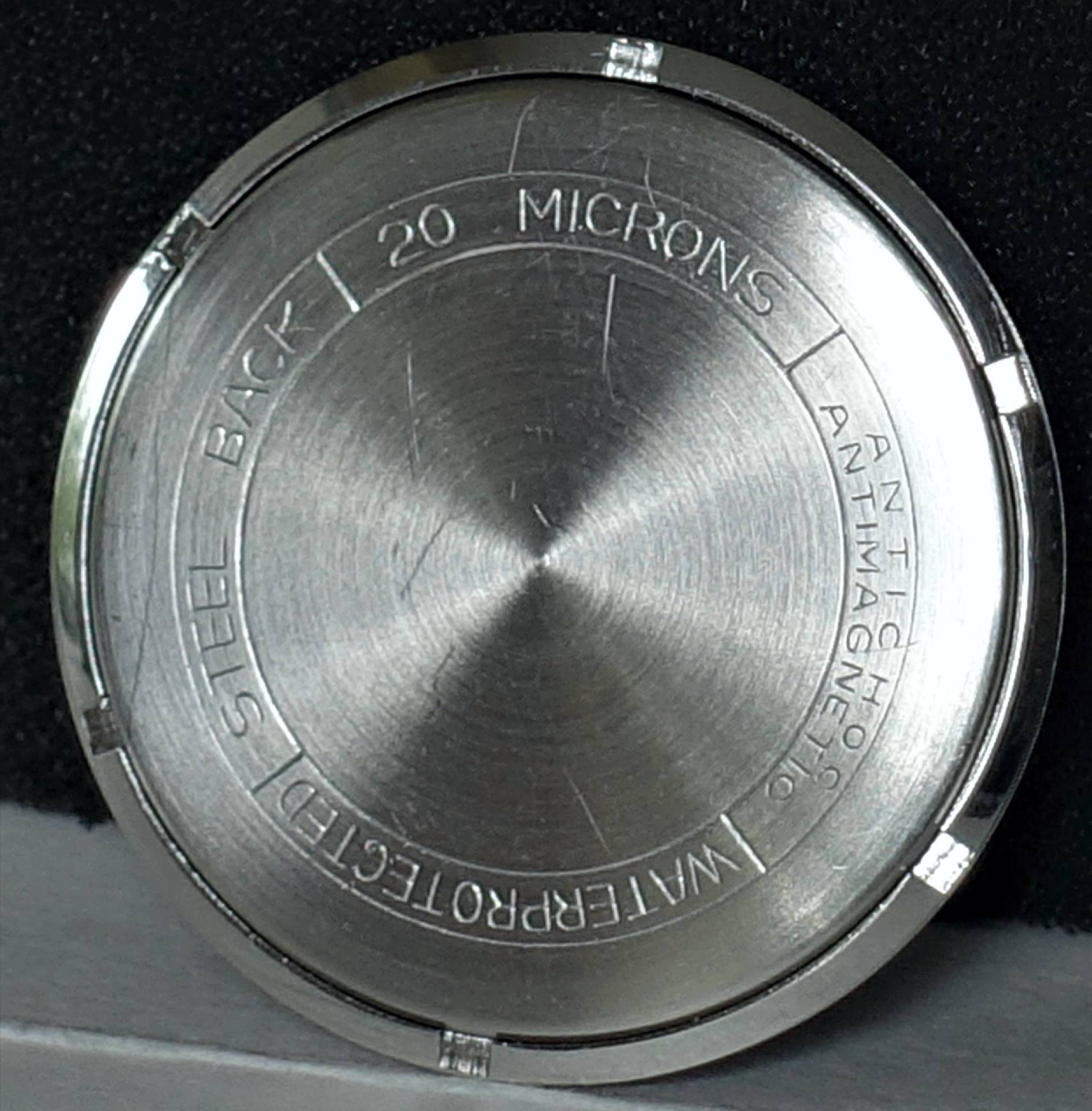 Runder silberfarbener Gehäuseboden für Armbanduhren aus Metall.