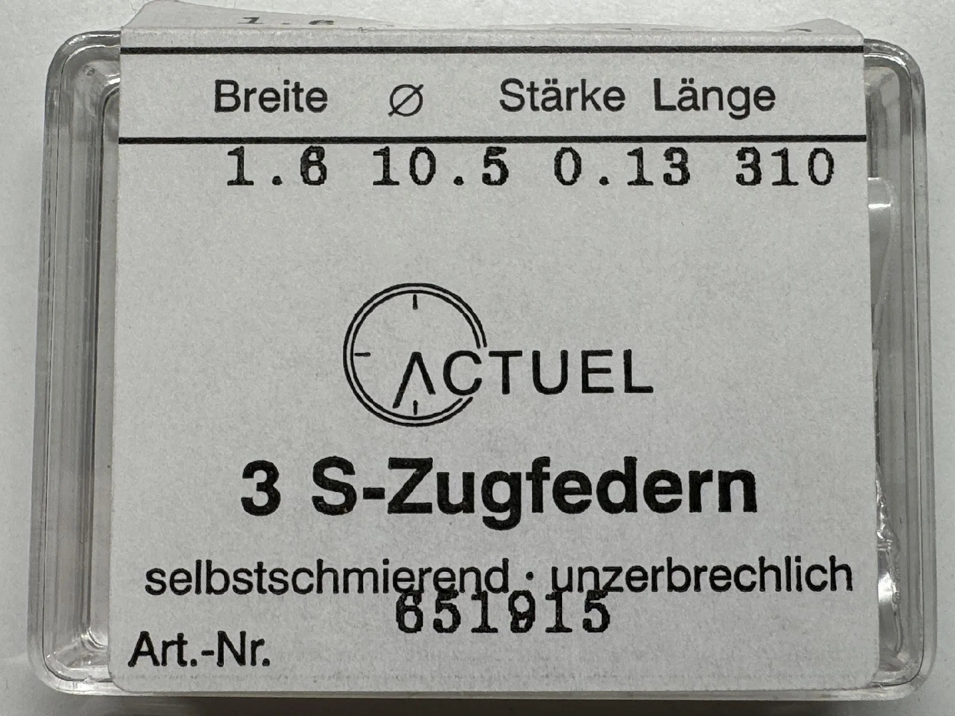 Drei silberfarbene Zugfedern für Uhren in transparenter Verpackung.
