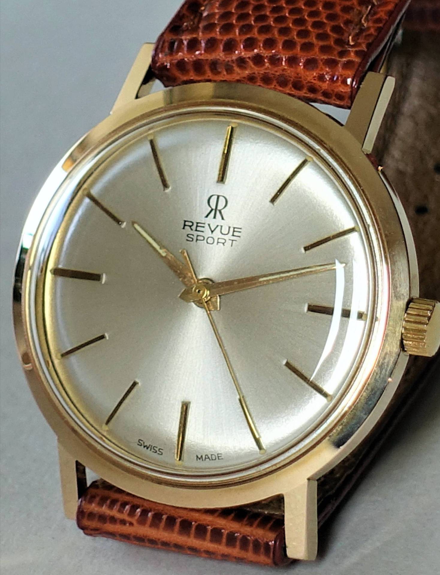 Goldfarbene Armbanduhr mit hellem Zifferblatt und braunem Lederarmband.