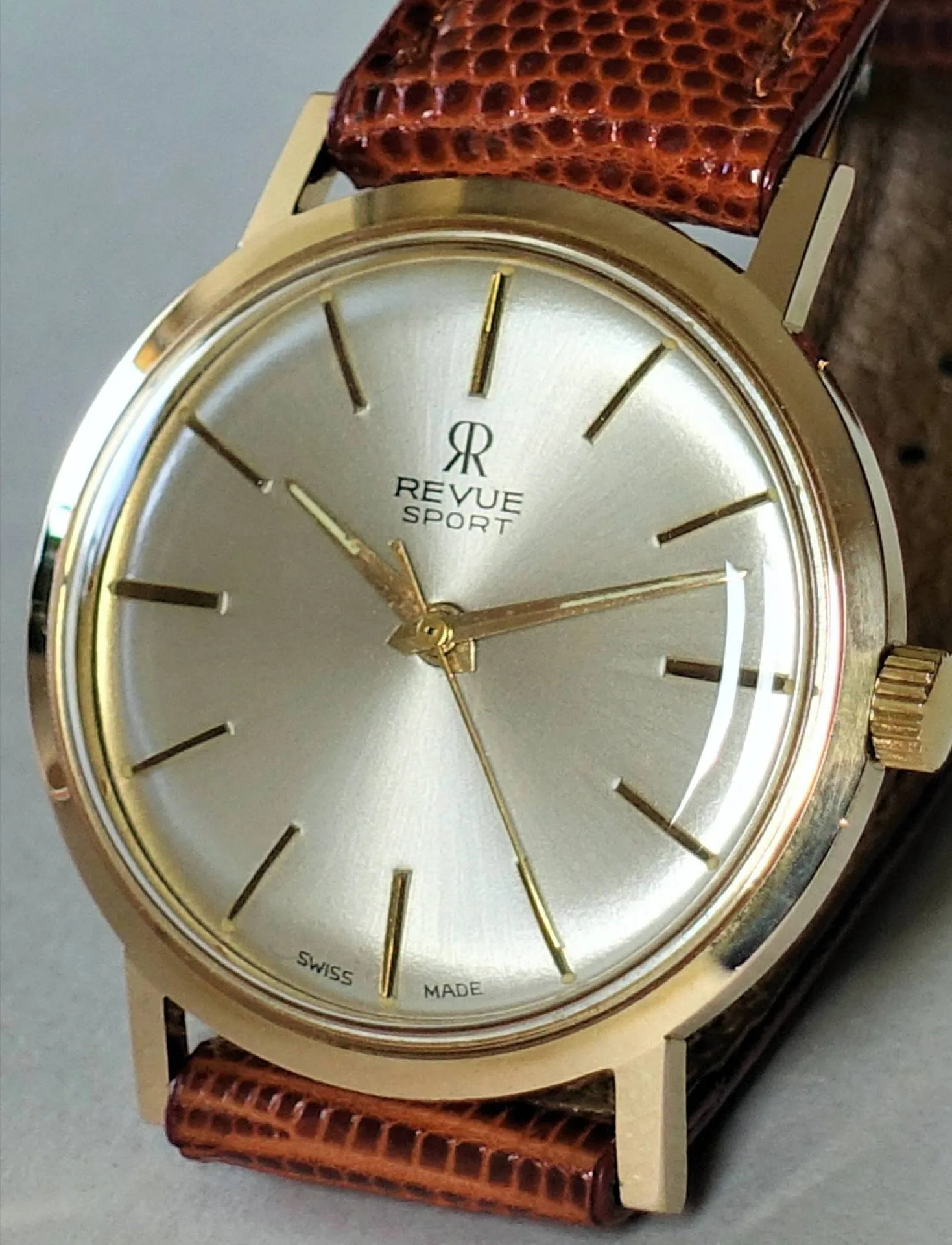 Goldfarbene Armbanduhr mit hellem Zifferblatt und braunem Lederarmband.