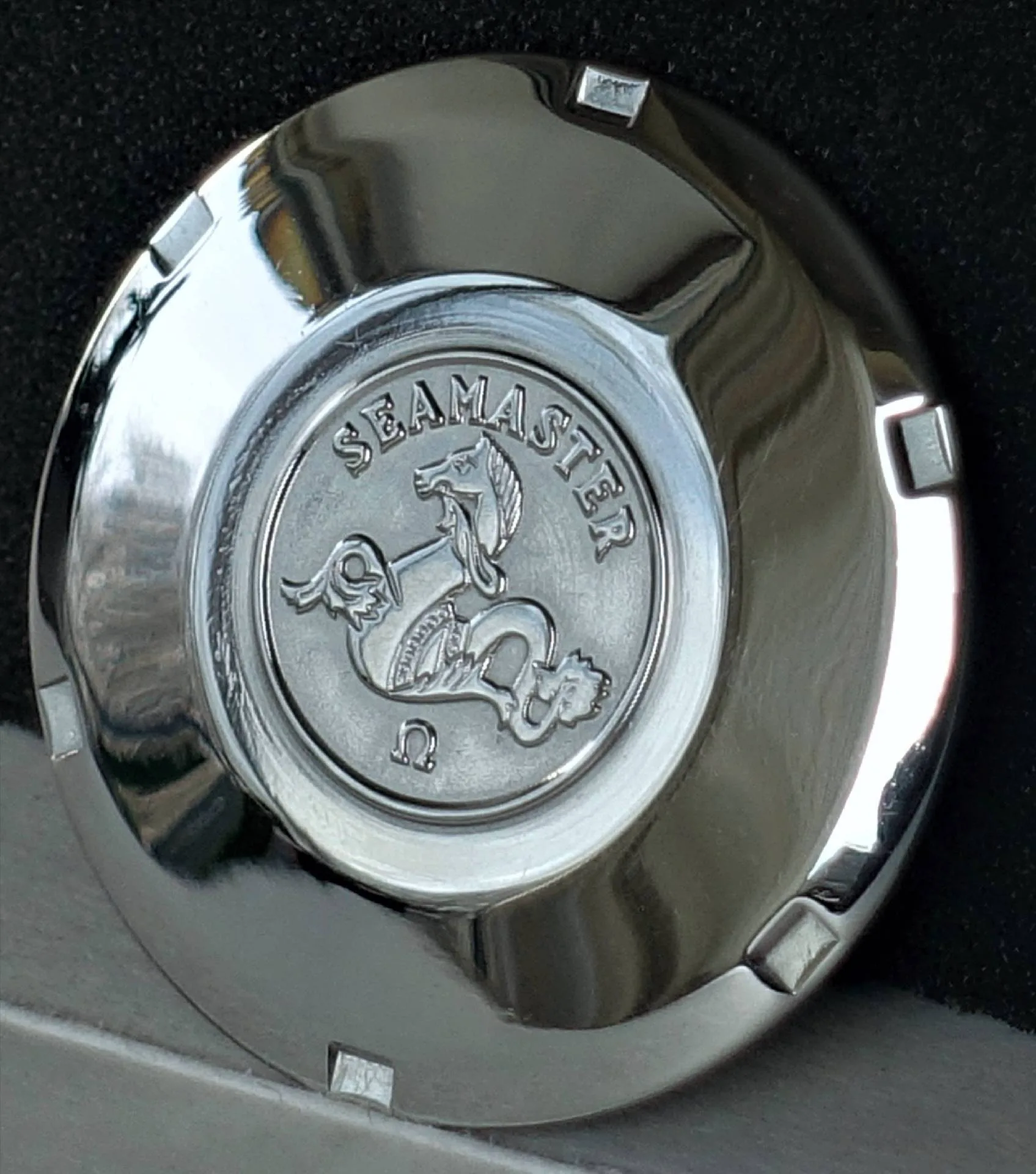Silberfarbener Gehäuseboden mit Gravur und Schriftzug "Seamaster" für Armbanduhren.