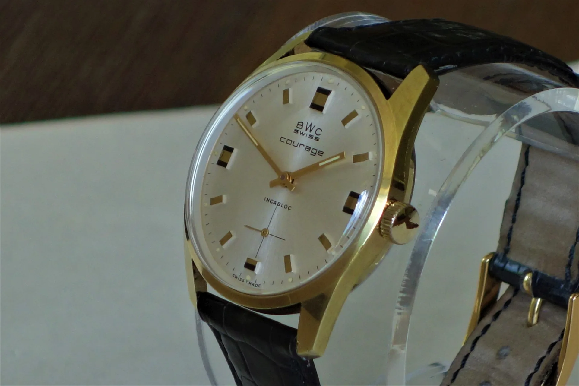 BWC Swiss Armbanduhr gold Klassische Armbanduhr mit goldfarbenem Gehäuse, hellem Zifferblatt und schwarzem Lederarmband.