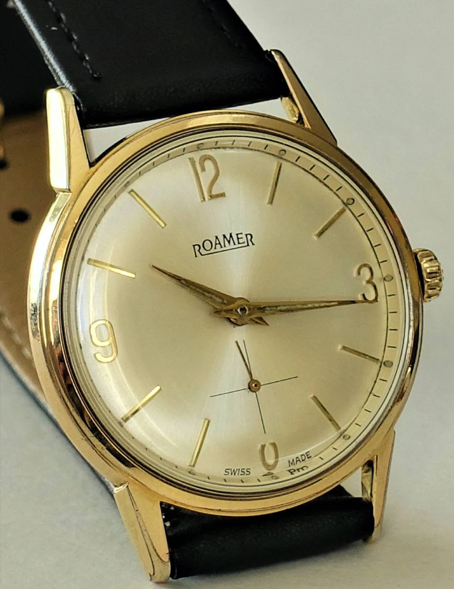 Roamer Armbanduhr goldfarben Goldfarbene Armbanduhr mit hellem Zifferblatt und schwarzem Armband.