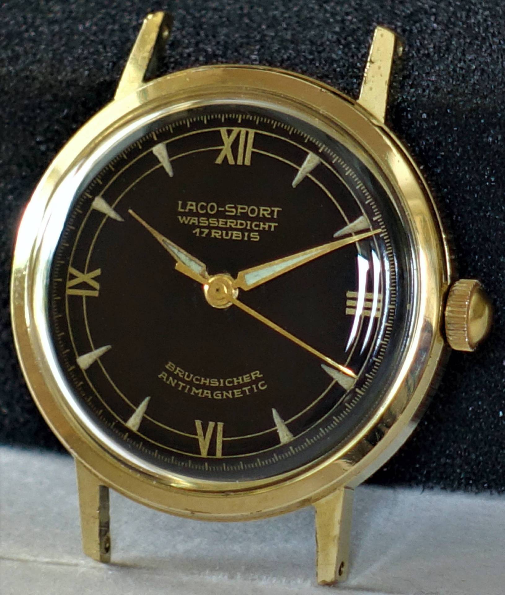 Schwarze Armbanduhr mit goldfarbenem Gehäuse und römischen Ziffern.