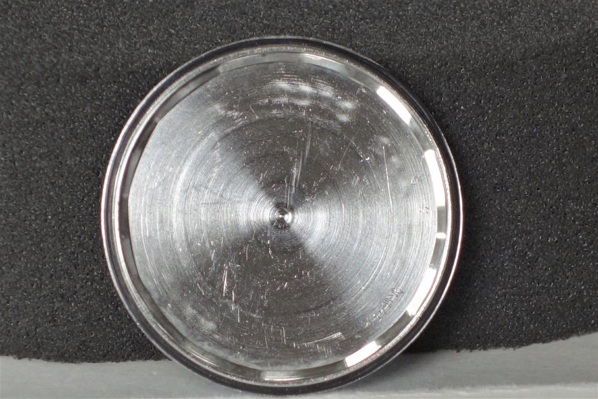 Runder silberfarbener Uhrenboden aus Metall.