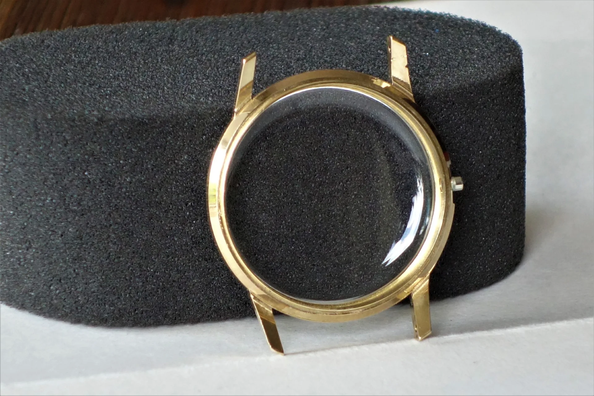 Rundes Uhrgehäuse in goldfarbener Optik mit transparentem Uhrglas.