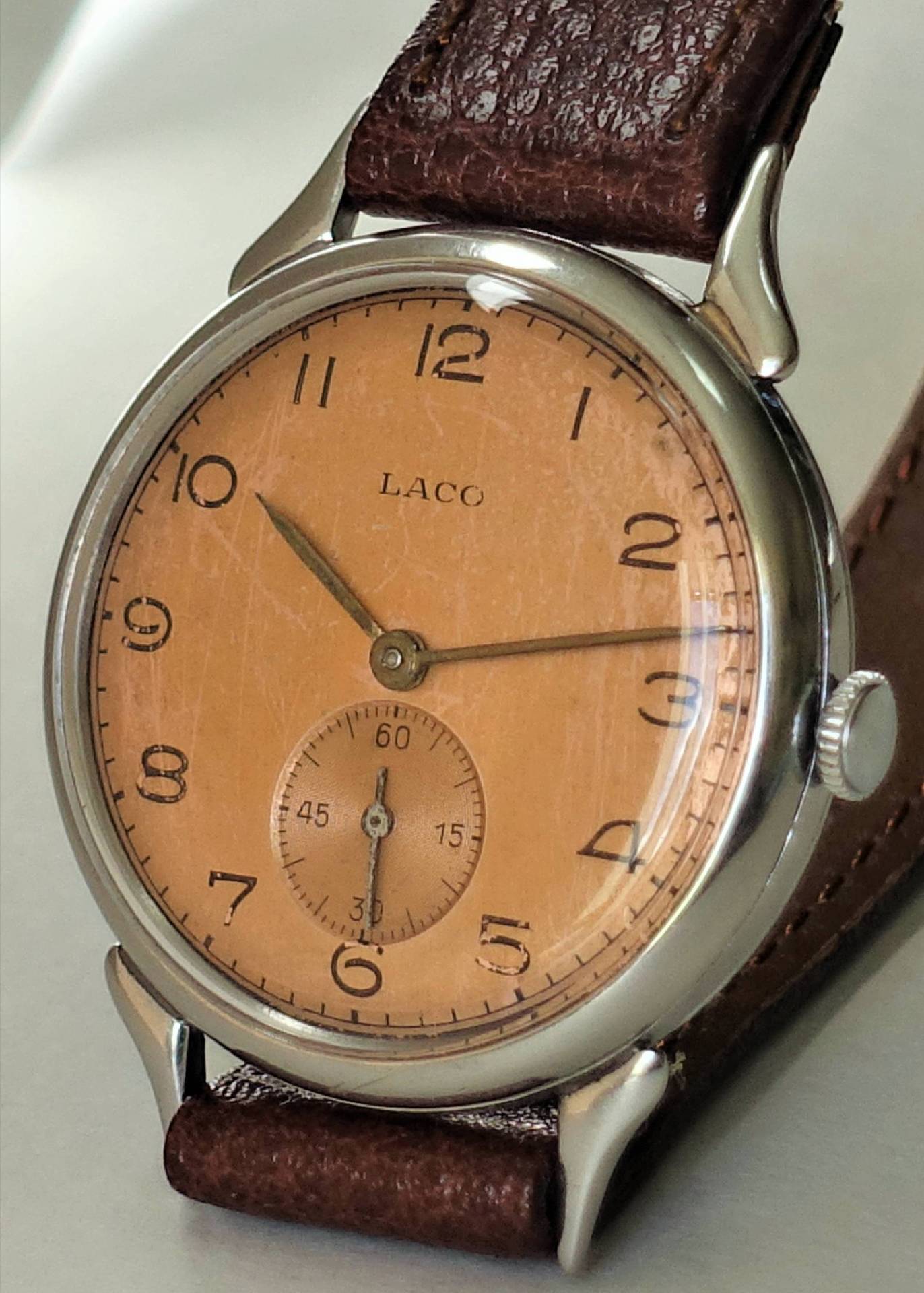 Braune Armbanduhr mit beigem Zifferblatt und kleiner Sekunde, Lederarmband und silberfarbenem Gehäuse.