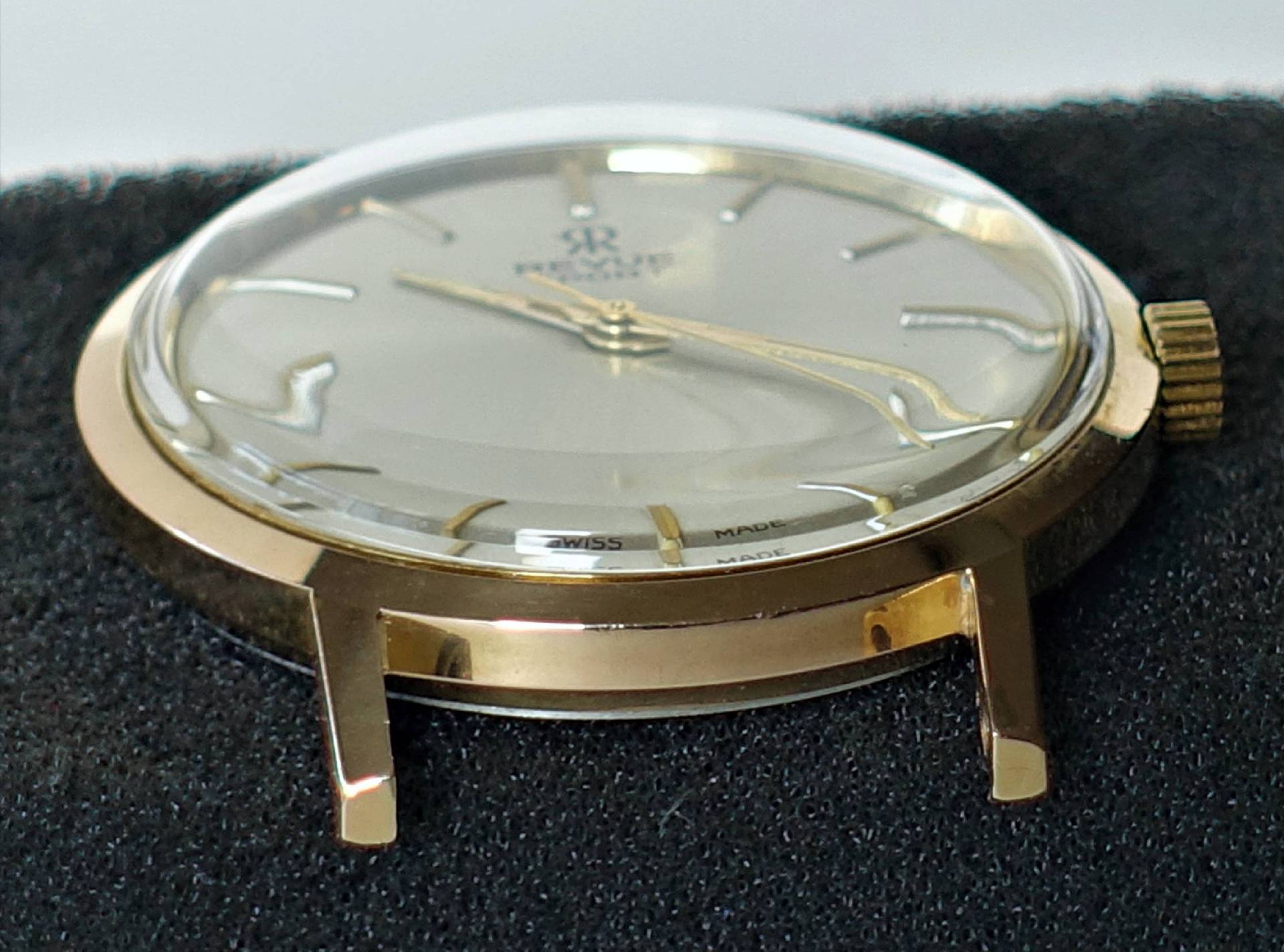 Flache Armbanduhr mit goldfarbenem Gehäuse und hellem Zifferblatt.