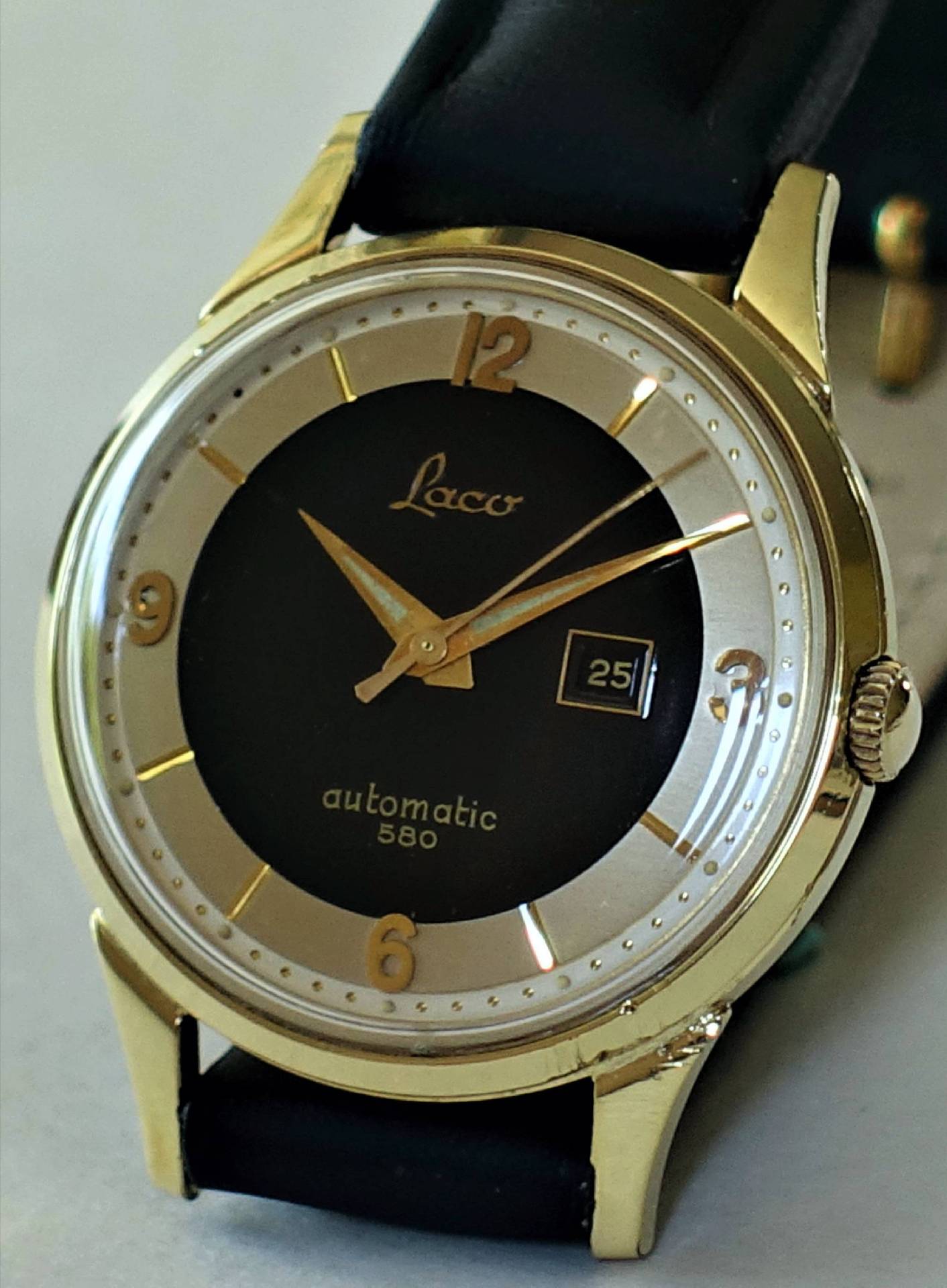 Goldfarbene Armbanduhr mit schwarzem Zifferblatt und Datumsanzeige.