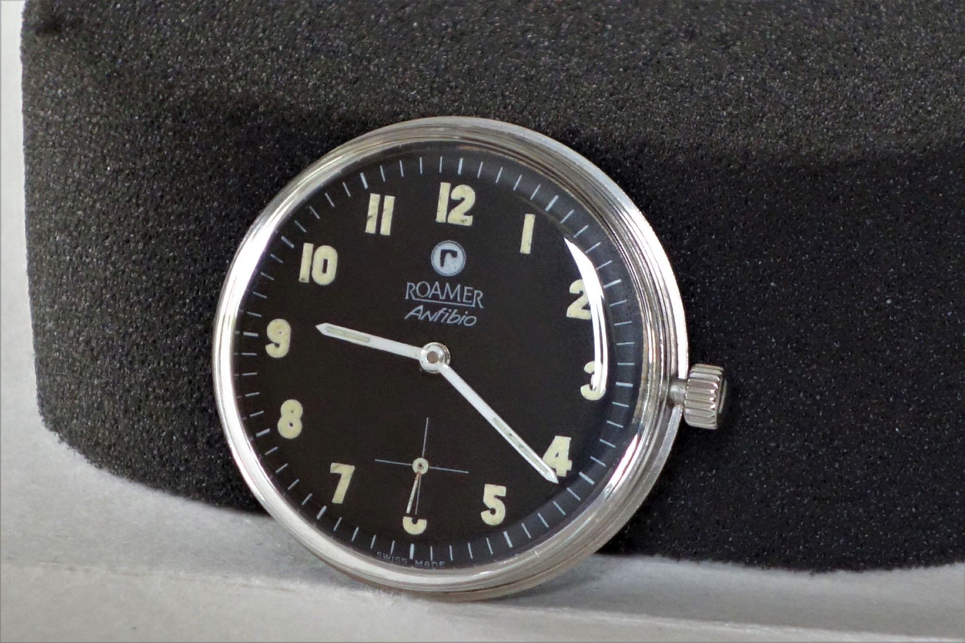 Schwarze Armbanduhr mit silberfarbenem Gehäuse und Leuchtziffern.