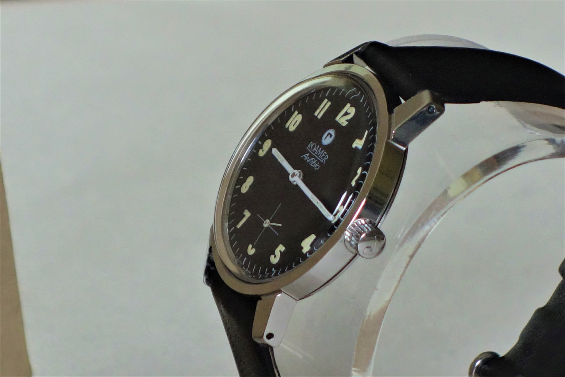 Schwarze Armbanduhr mit hellem Zifferblatt und schwarzem Armband.