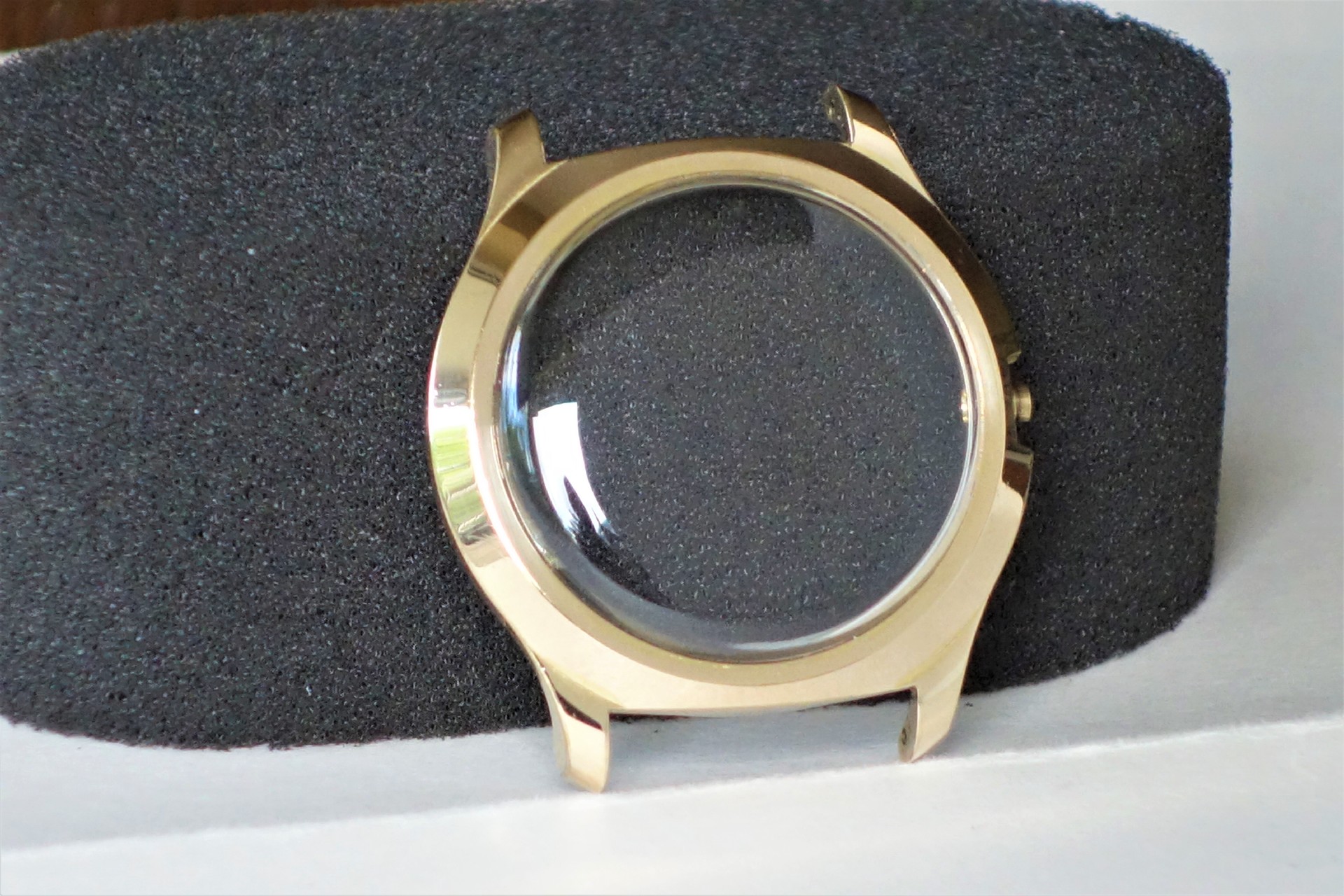 Rundes Uhrengehäuse in goldfarbener Optik mit transparentem Uhrglas.