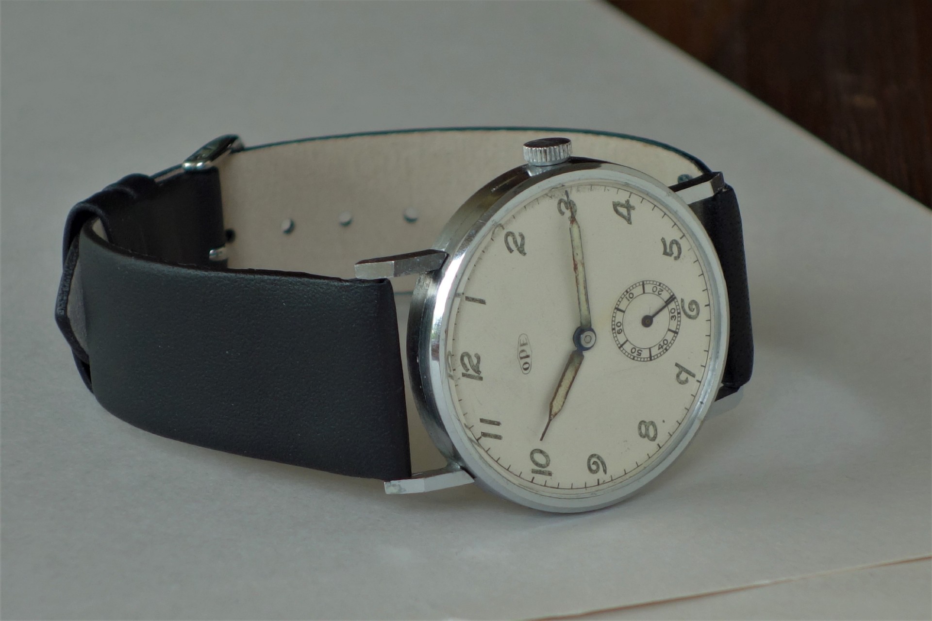 Mechanische Armbanduhr mit silberfarbenem Gehäuse, hellem Zifferblatt und schwarzem Armband.