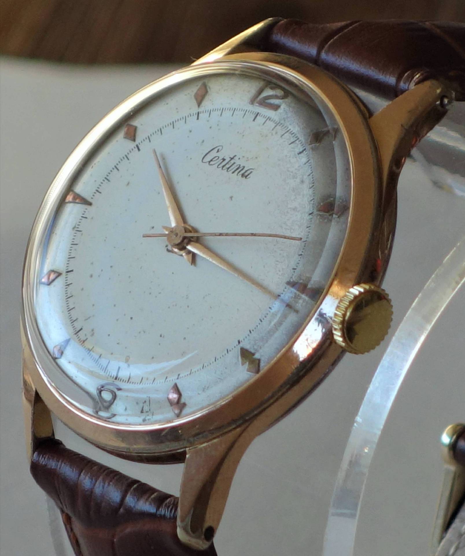 Analoge Armbanduhr mit hellem Zifferblatt, braunem Armband und goldfarbenem Gehäuse.