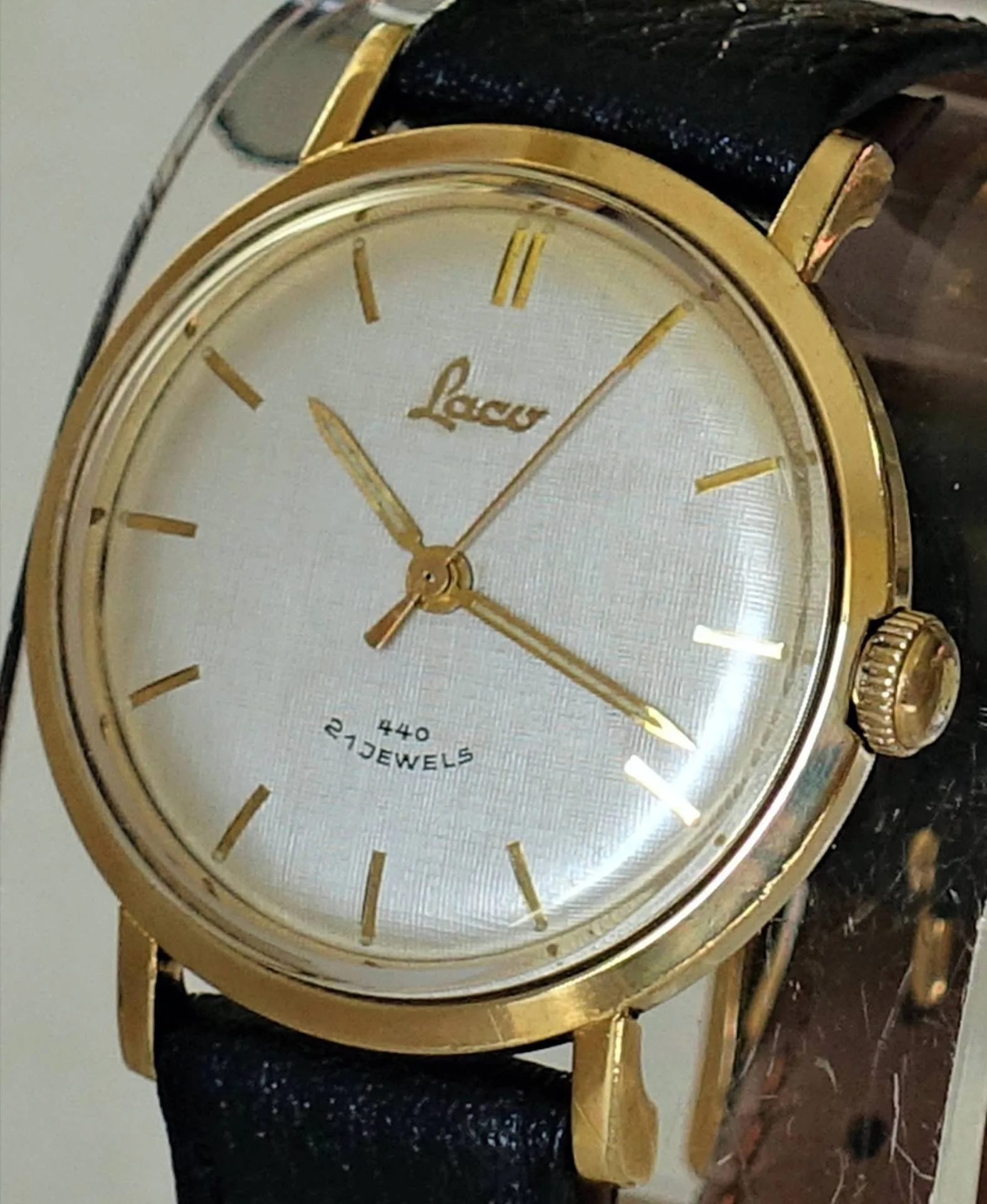 Goldfarbene Armbanduhr Laco Goldfarbene Armbanduhr mit hellem Zifferblatt, schwarzen Lederarmband und goldenen Zeigern.