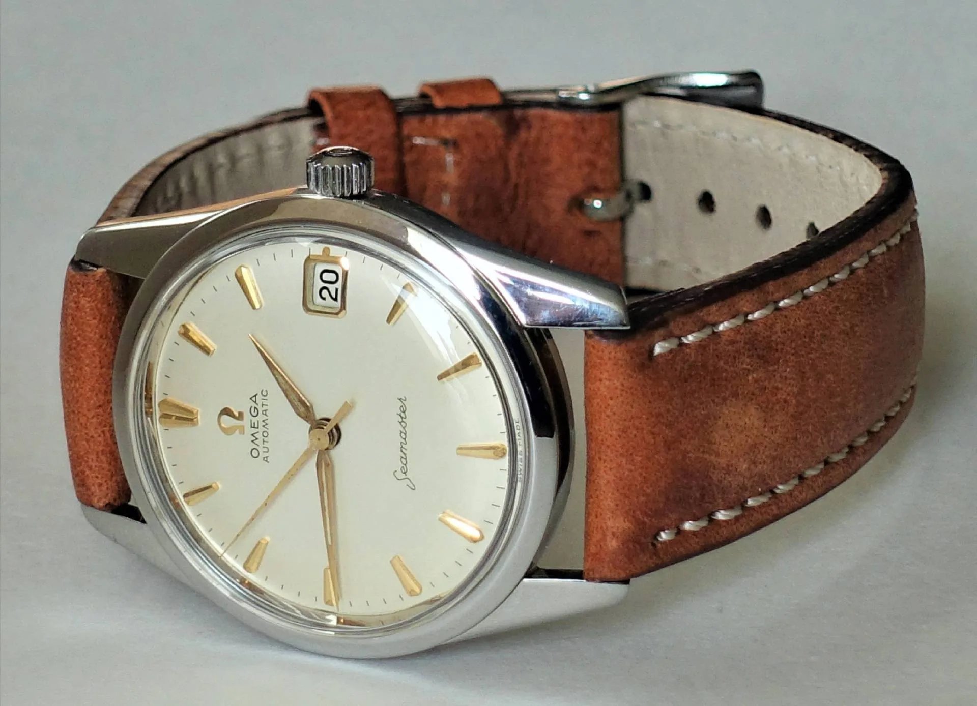 Omega Seamaster Armbanduhr Silberfarbene Armbanduhr mit beigem Zifferblatt, goldfarbenen Indizes und braunem Lederarmband.