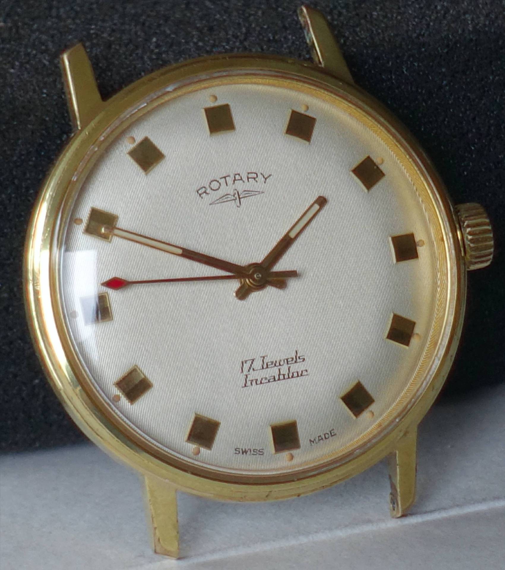 Goldfarbene Armbanduhr mit hellem Zifferblatt und eckigen Stundenmarkierungen.