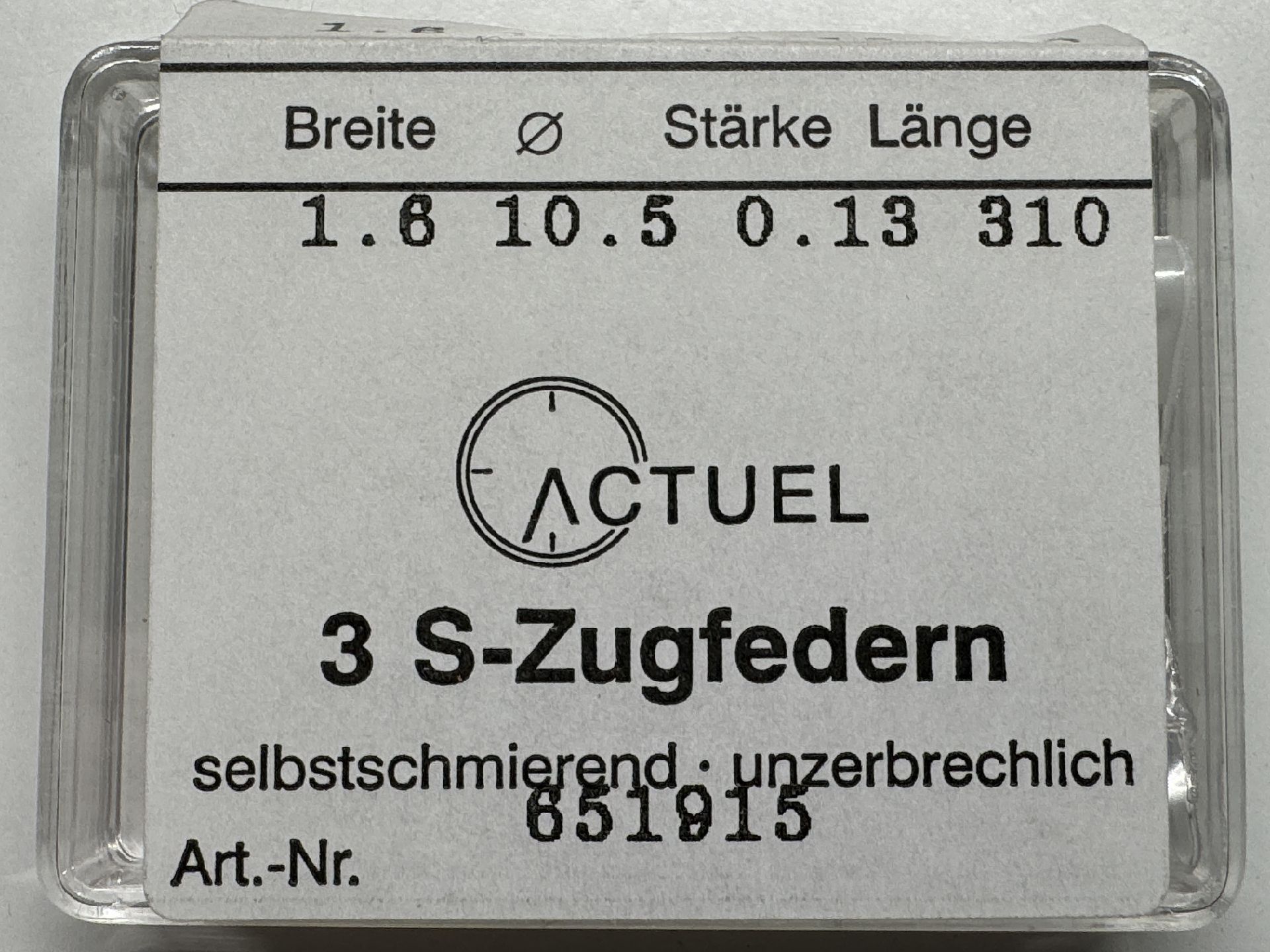 Drei silberfarbene Zugfedern für Uhren in transparenter Verpackung.