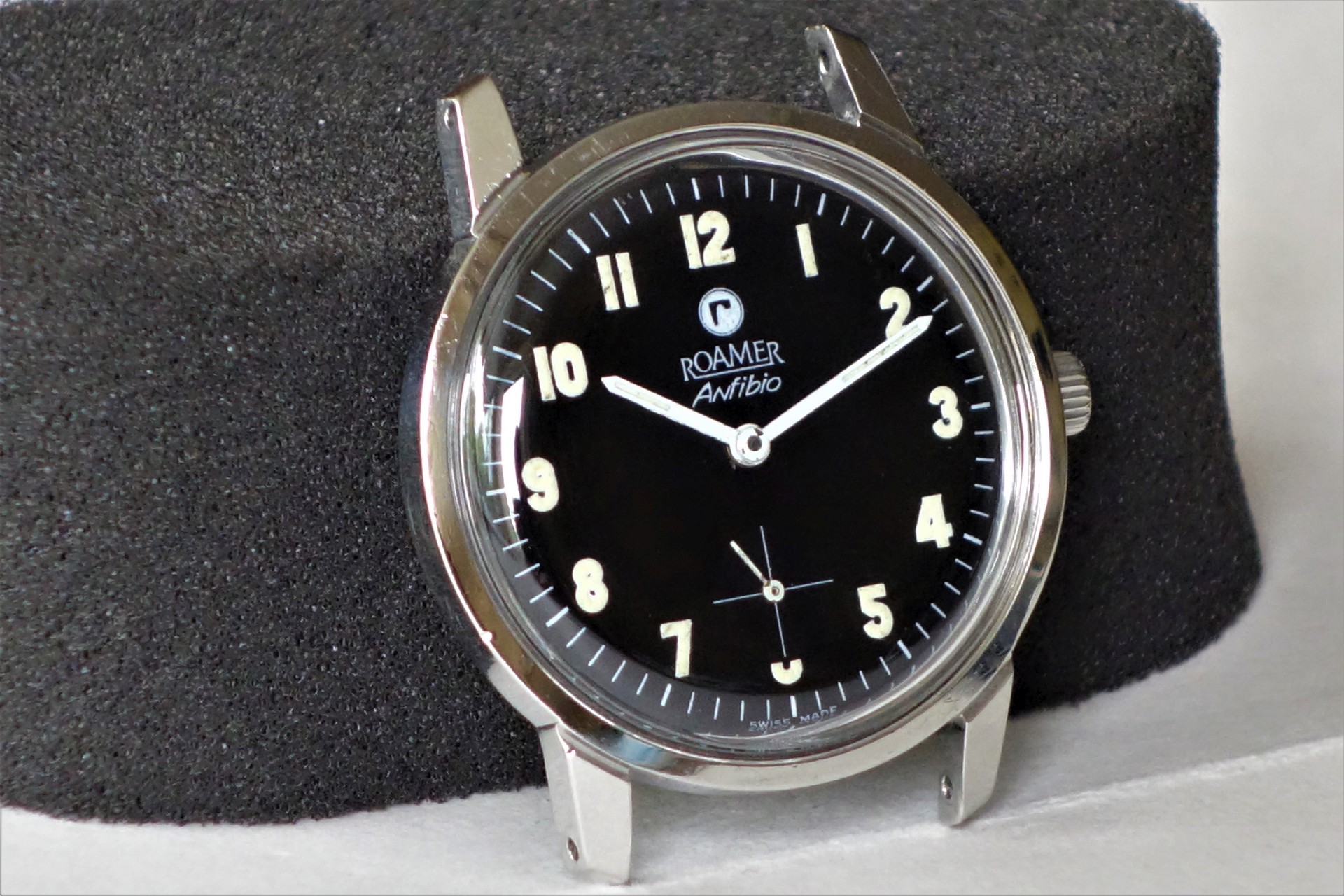 Schwarze Armbanduhr mit silberfarbenem Gehäuse und Leuchtziffern.